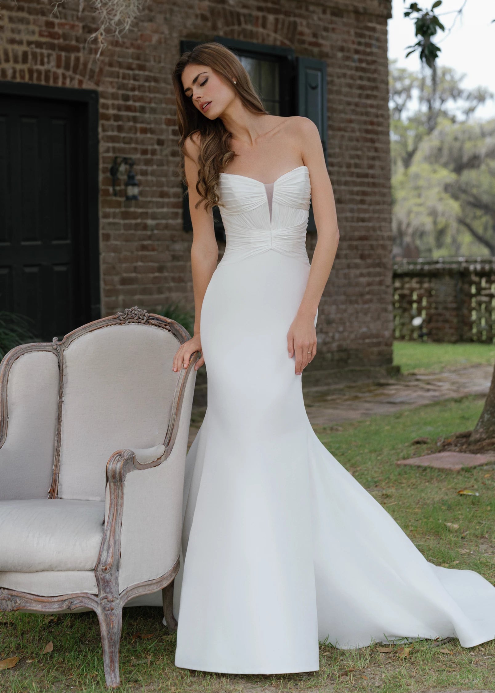 The Montagu gown is a trumpet gown of Italian Kalika with a narrow plunging V-neckline bodice, intricately pleated in Silk Satin Chiffon, and buttons to the top of the godet in Silk White.