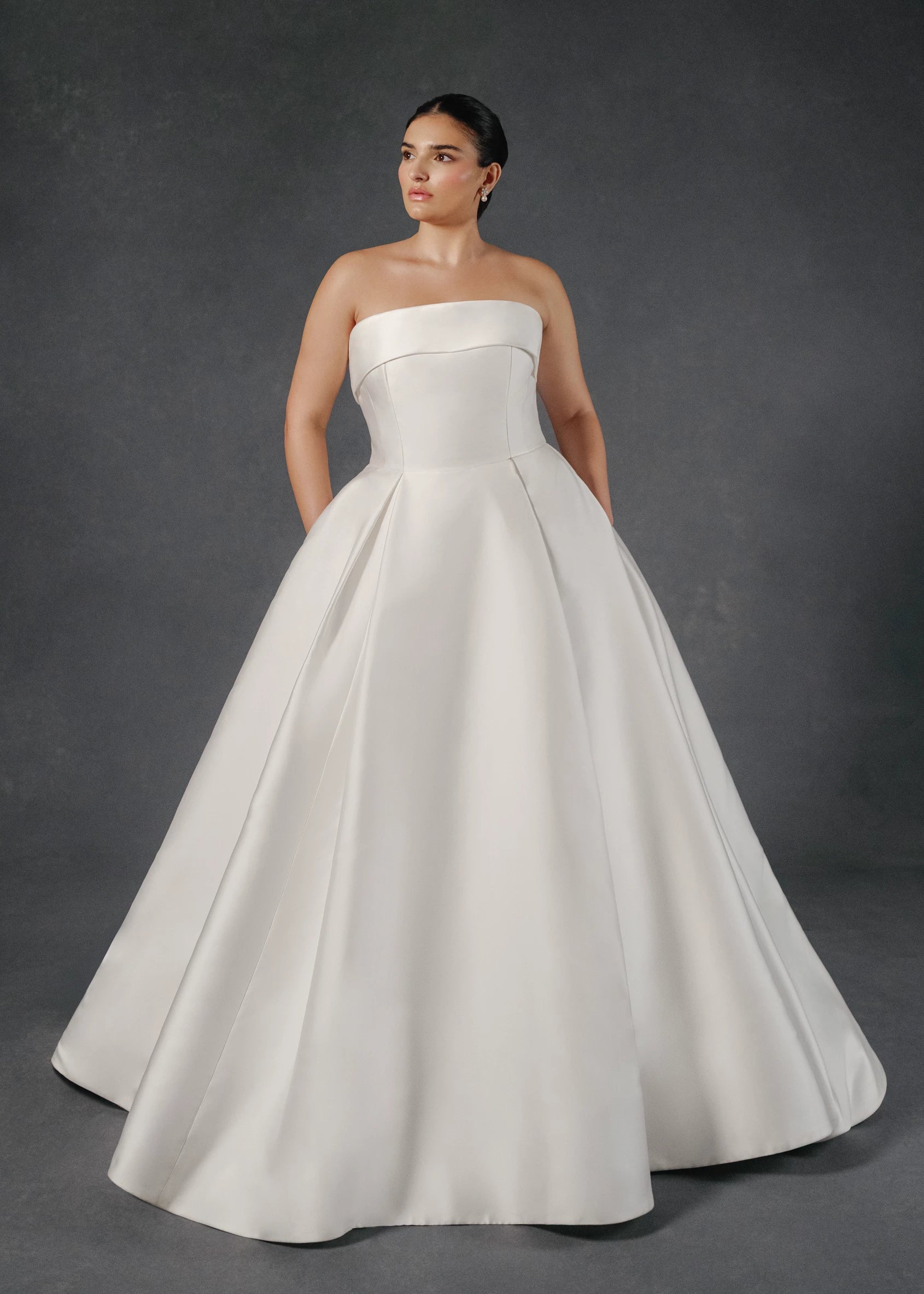 The Burke gown is a box pleated ballgown of Mikado Scuba with skirt slit and cuff neckline accented with Faille and Silk Organza floral appliqués in Silk White.