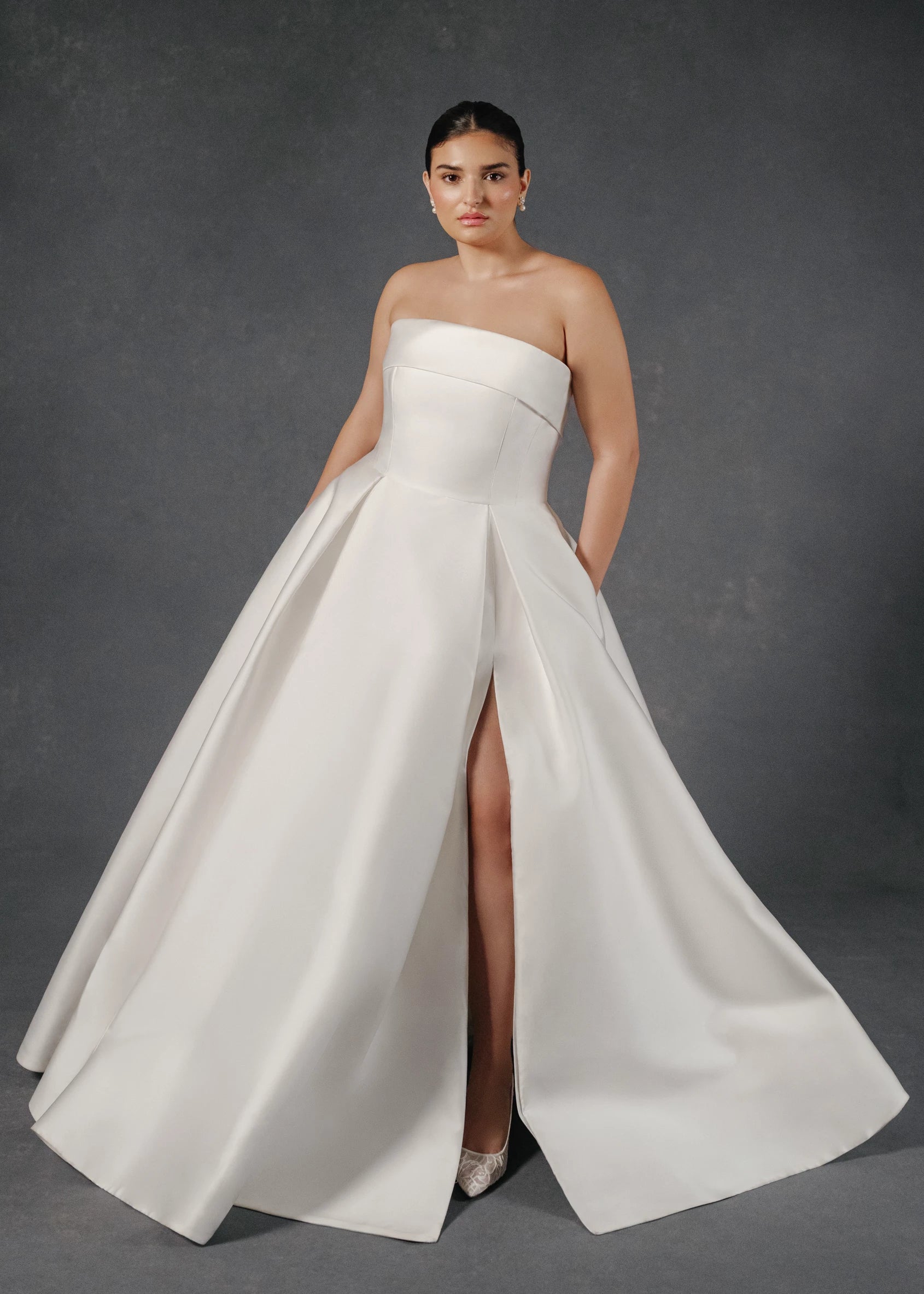 The Burke gown is a box pleated ballgown of Mikado Scuba with skirt slit and cuff neckline accented with Faille and Silk Organza floral appliqués in Silk White.
