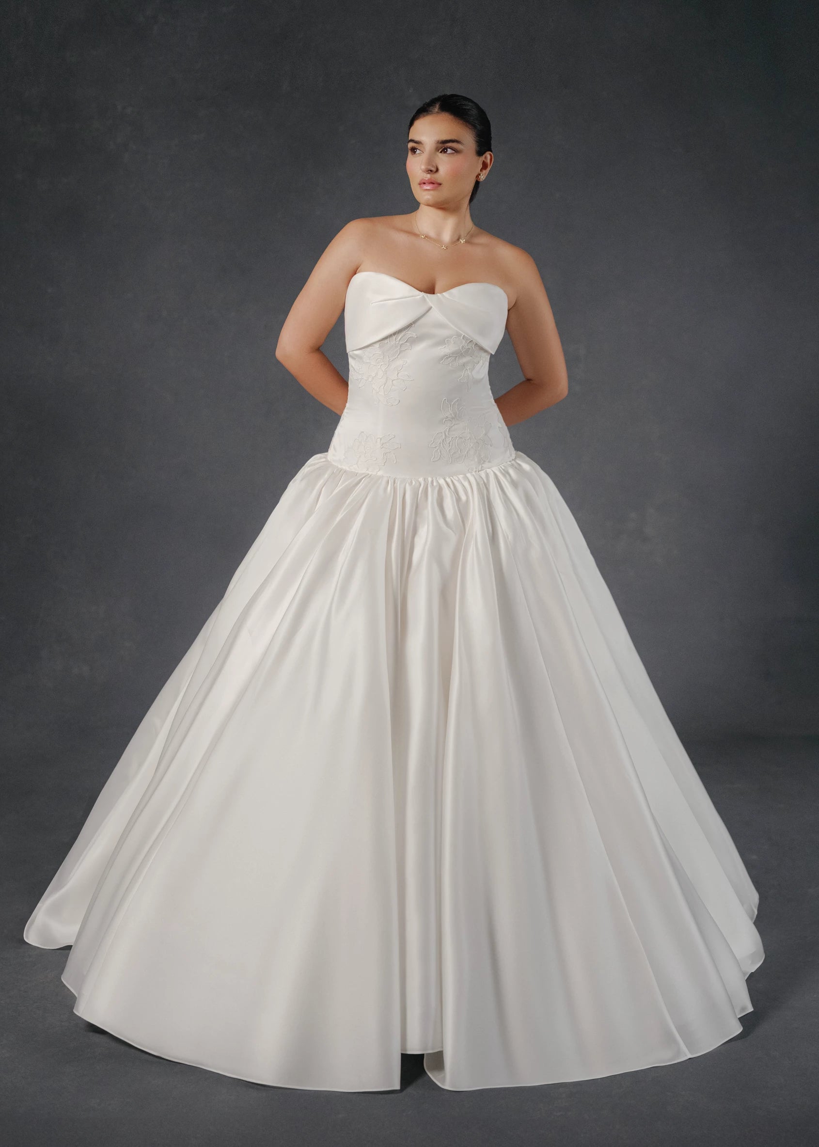 The Noblesse gown is a contour strapless drop waist ball gown of Silk Satin Organza with a draped neckline, delicate French Alençon lace appliqués, and a gathered skirt finished with buttons to the hem in Silk White.