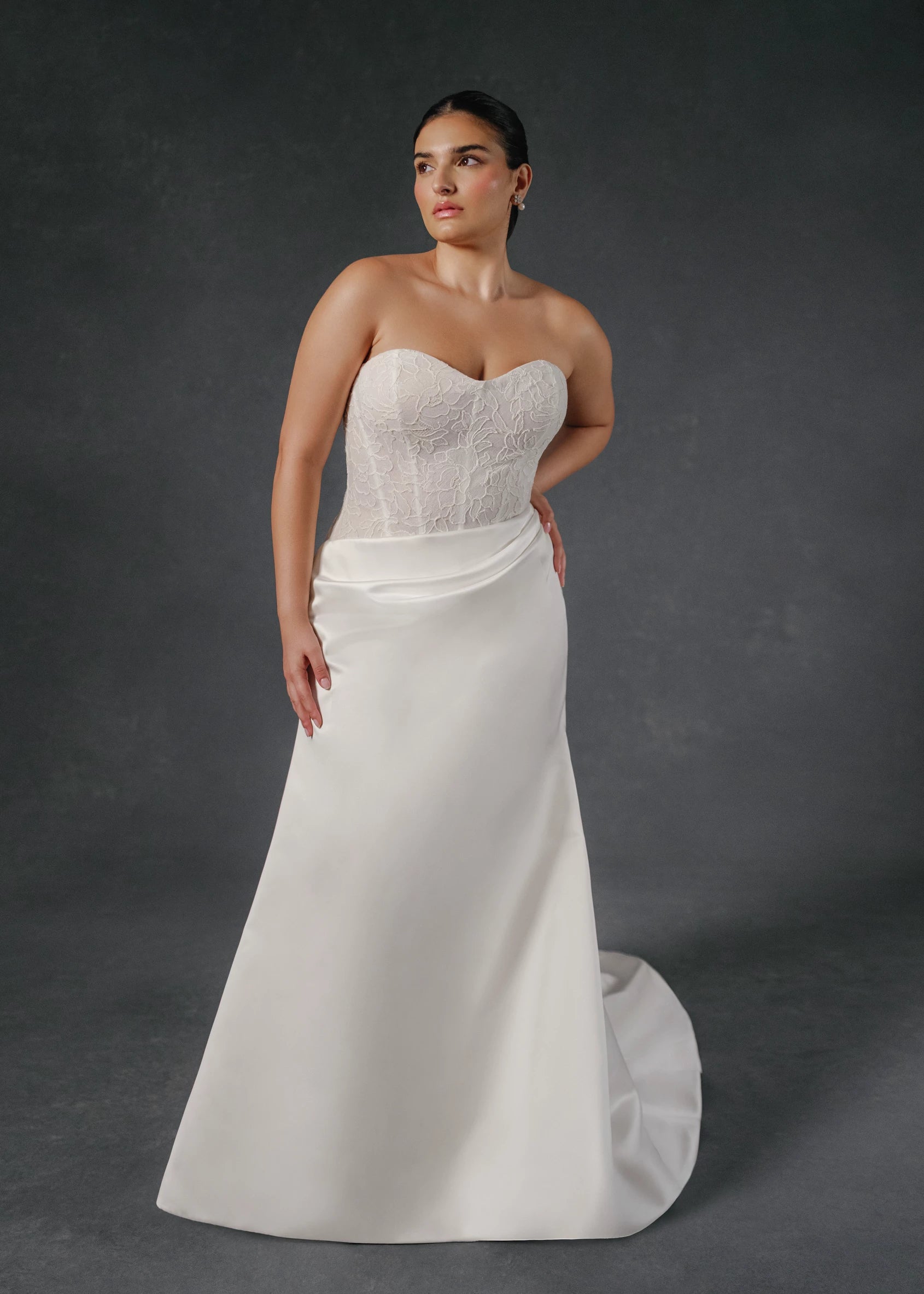 The Sully gown is an elongated corseted bodice accented with French Alenćon lace appliques, paired with trumpet skirt of Faille-Back Satin featuring soft draping at the waist in Silk White.