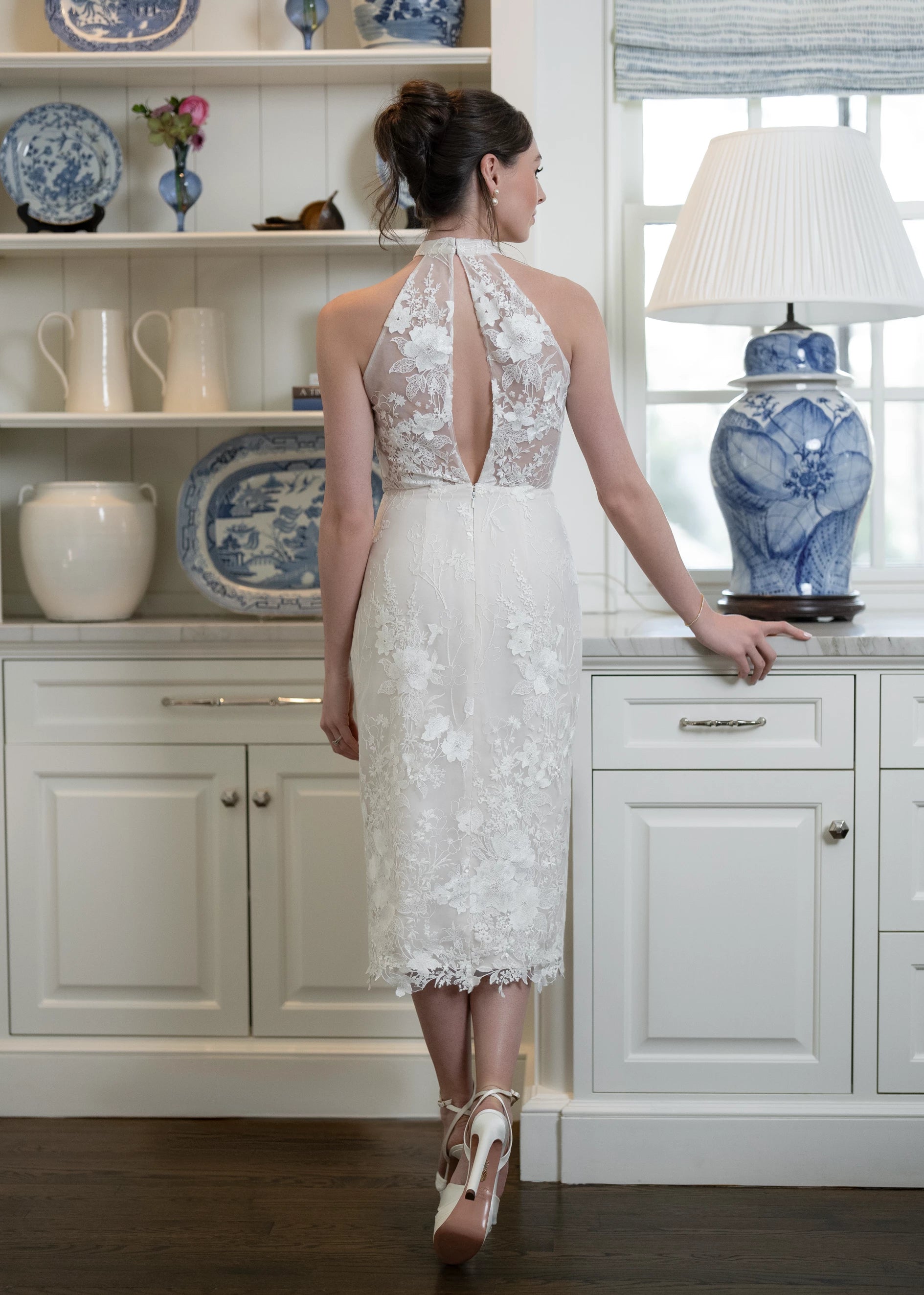 The back view of Anne Barge Anne Barge “Unforgettable” little white dress — halter midi dress with flattering draping and slit, comprised of intricate embroidery and a split open back detail in Silk White/Nude.
