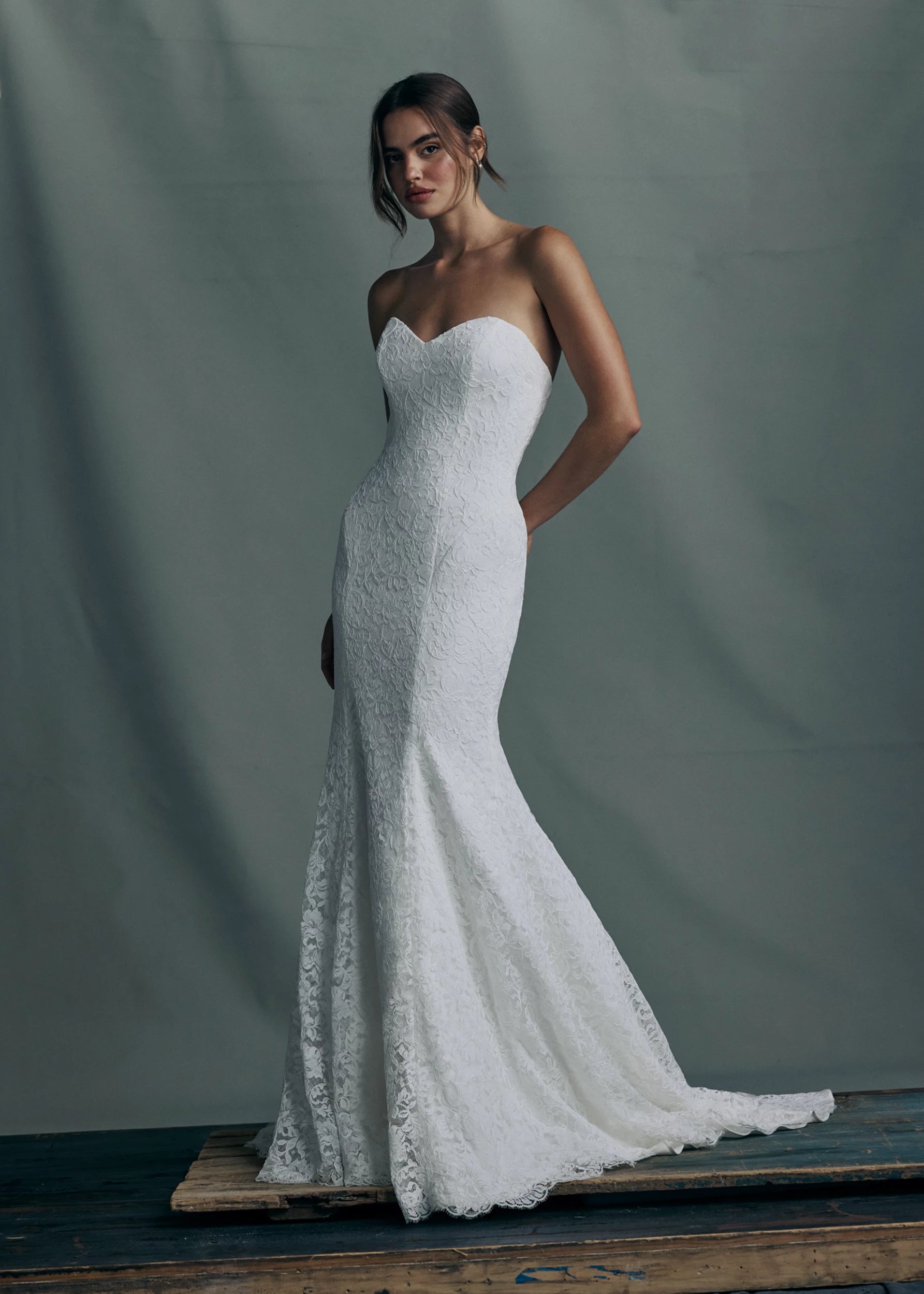 The Anouk gown by Anne Barge is a strapless deep sweetheart gown in Corded Scrolling Floral Lace, fitted through the hips into a softly flared hem in Silk White.