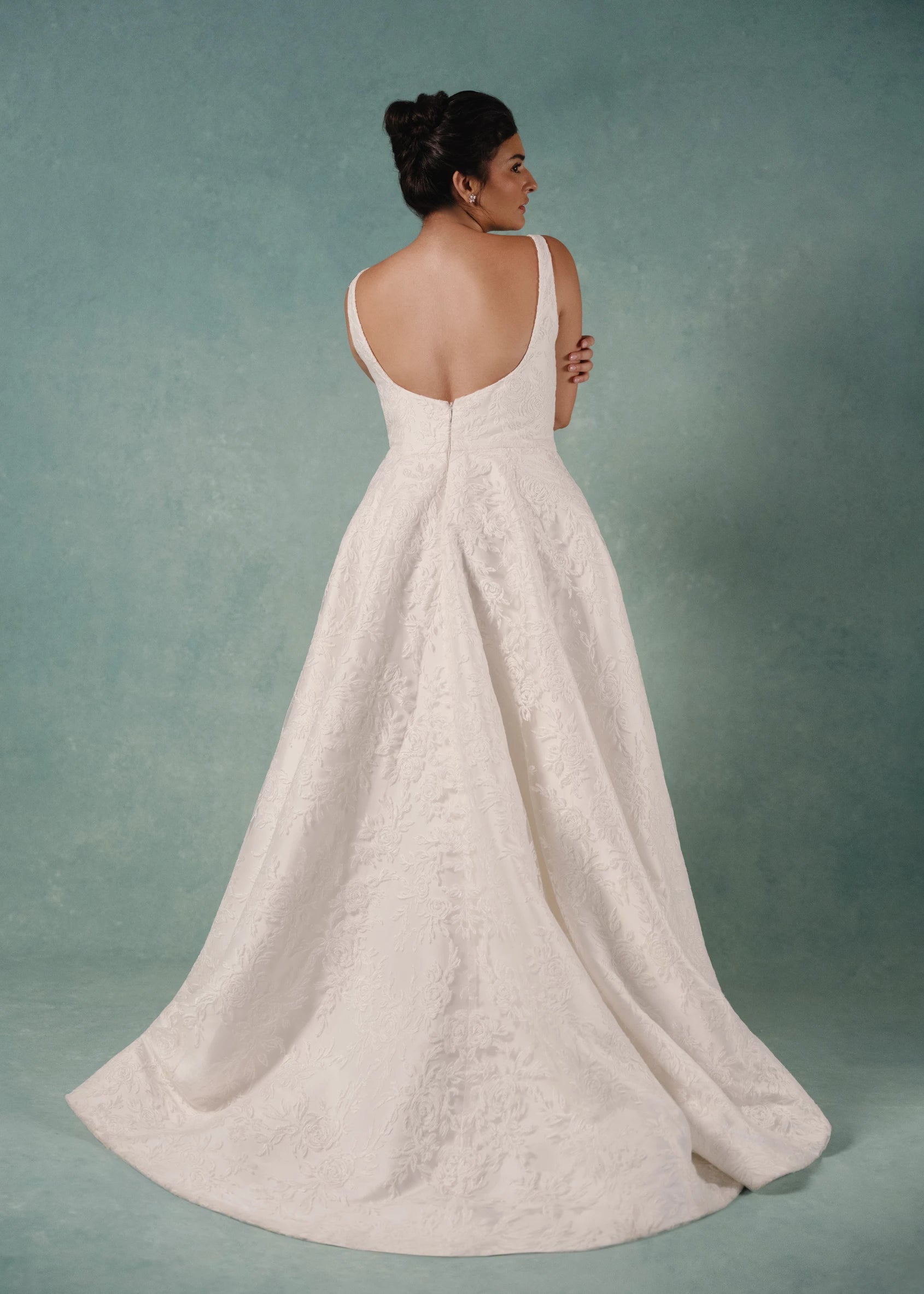 The Amelie gown is a scoop neck A-line gown in Soft Mikado with Thread-Sketched Floral Embroidery overlay and removeable Faille bow belt at the waist