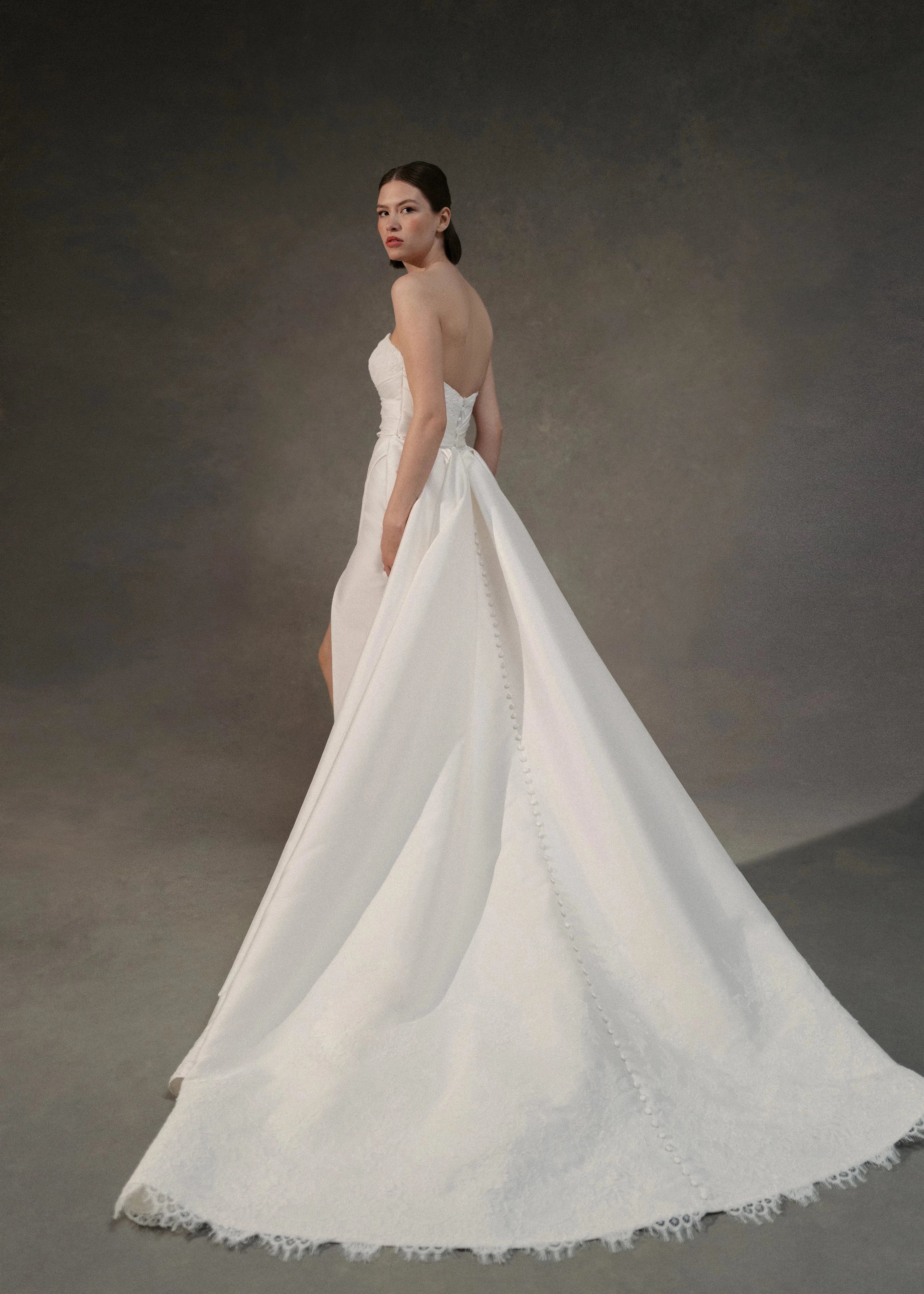 The Blue Willow Kaia Train is a dramatic detachable train of Soft Mikado, accented with a Corded Lace scalloped hem and buttons in Pearl.