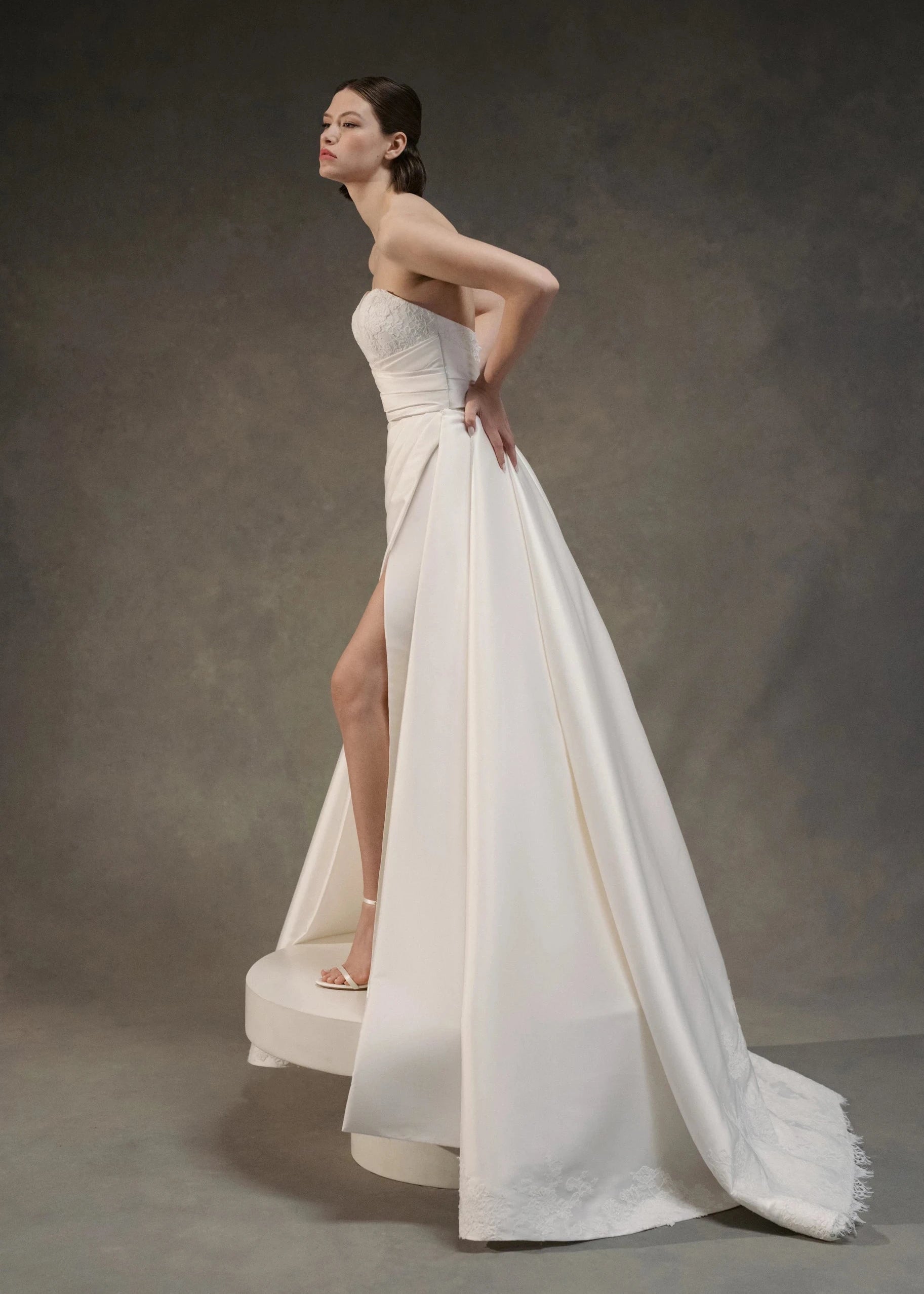 The Blue Willow Kaia Train is a dramatic detachable train of Soft Mikado, accented with a Corded Lace scalloped hem and buttons in Pearl.
