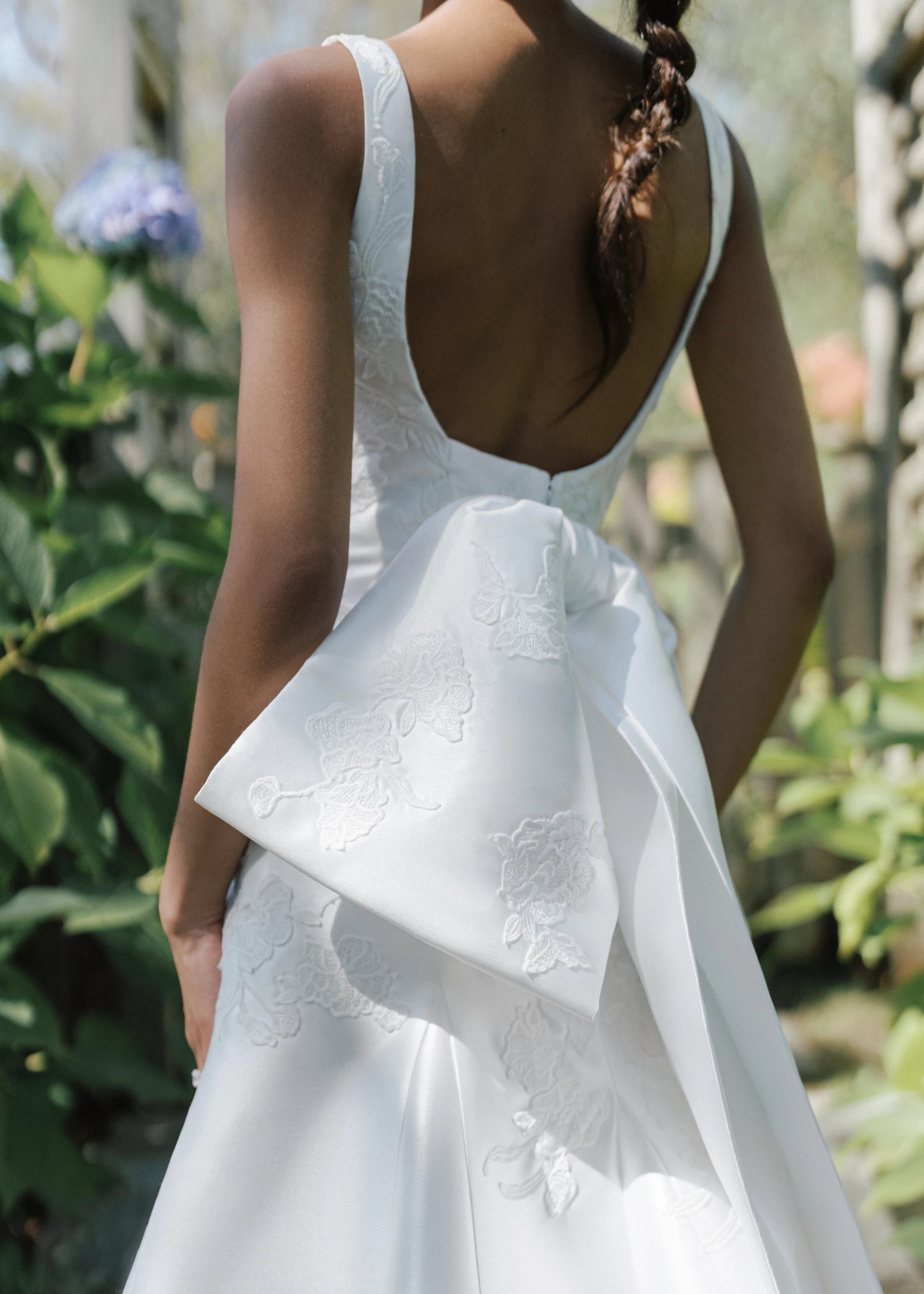 The Blue Willow Sayle Bow is an asymmetric bow of Mikado dotted with Floral Vine Embroidery appliqués in Silk White.