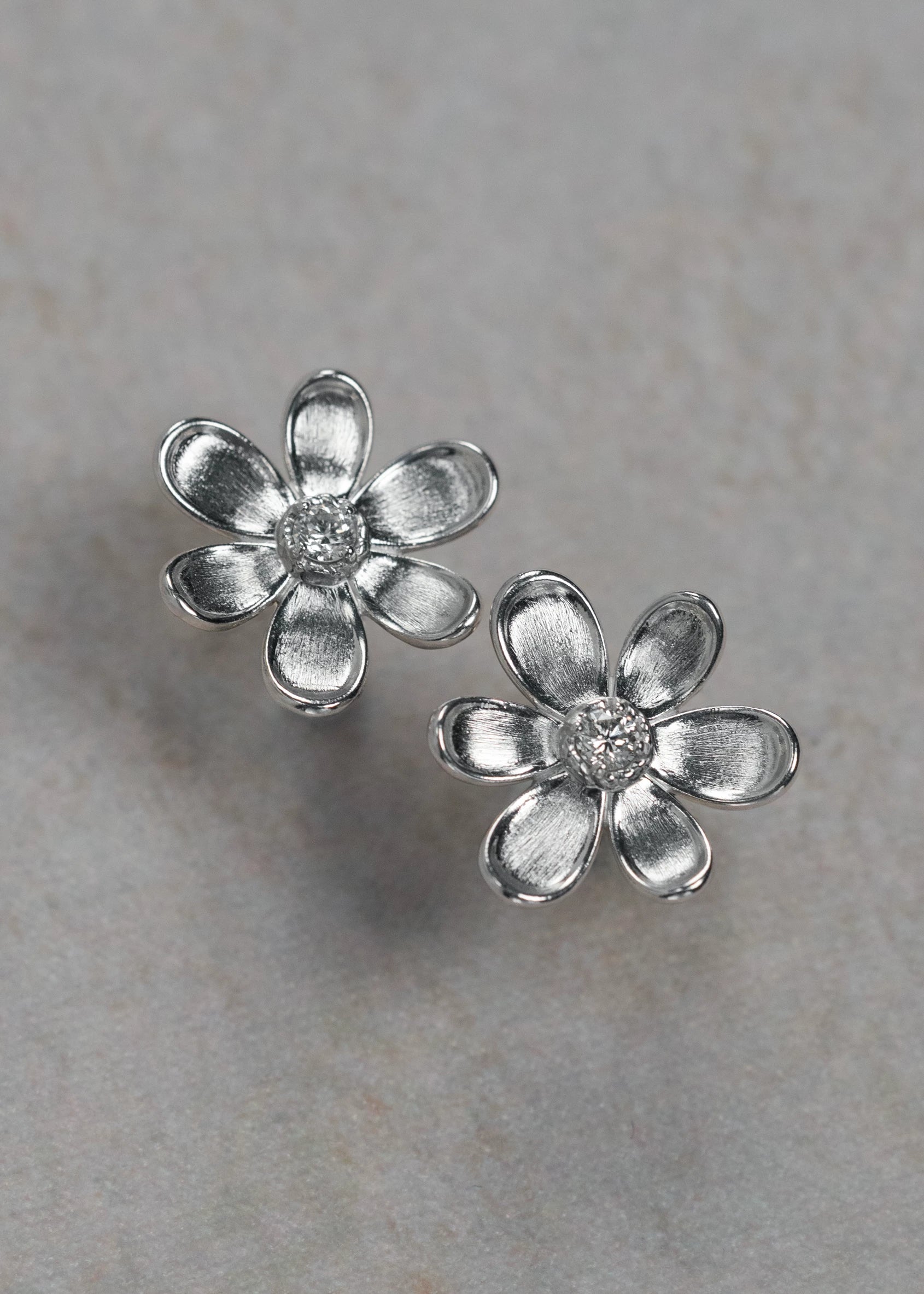 Designed by Atlanta jewelry designer Laura Pearce, delicate Daisy flower studs, featuring a 0.20 CTTW brilliant diamond, and available in 8K Yellow or White Gold.