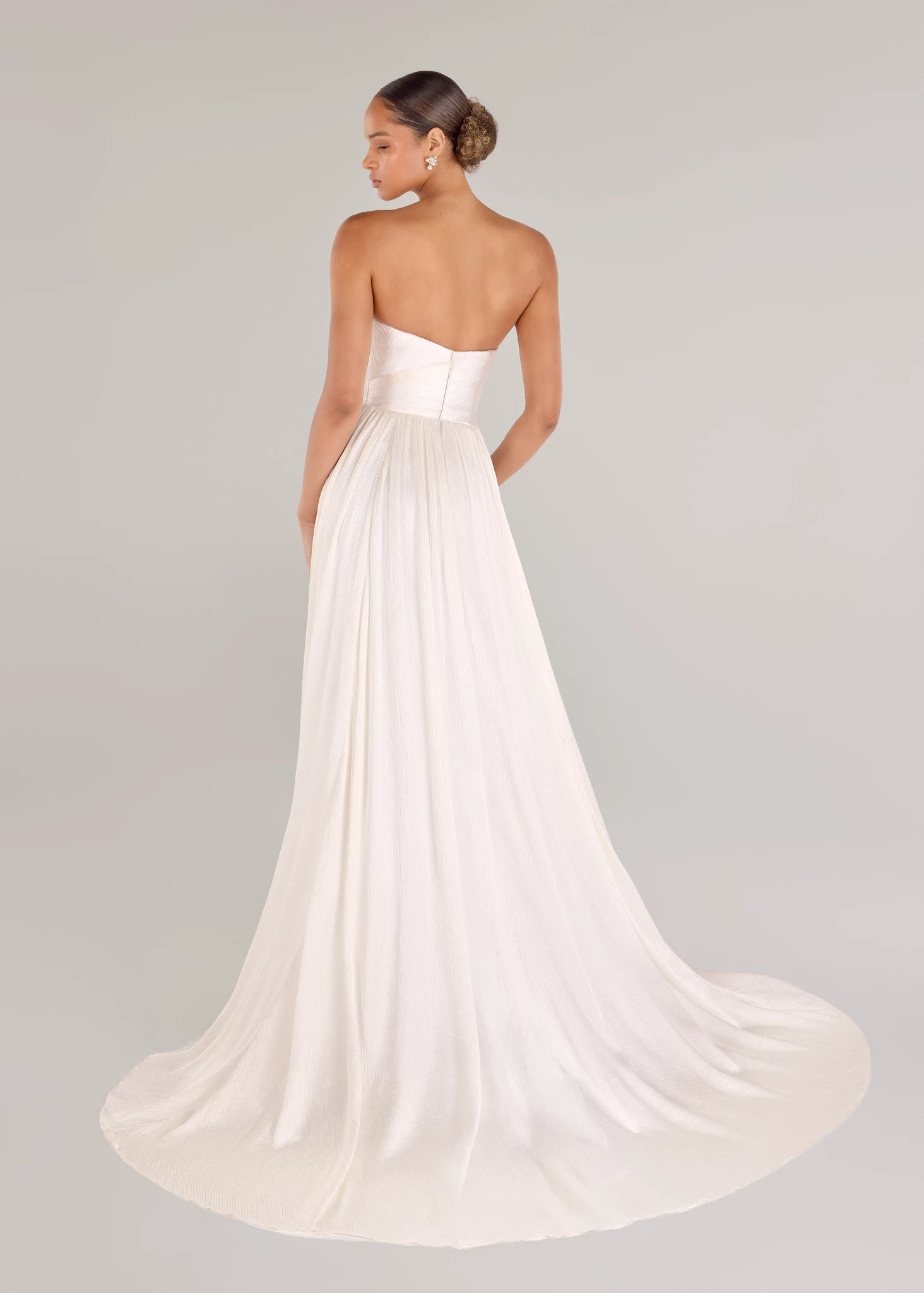 The Harelston gown is an A-line Crinkle Chiffon gown with softly gathered skirt and an asymmetrically pleated strapless bodice in Pearl.