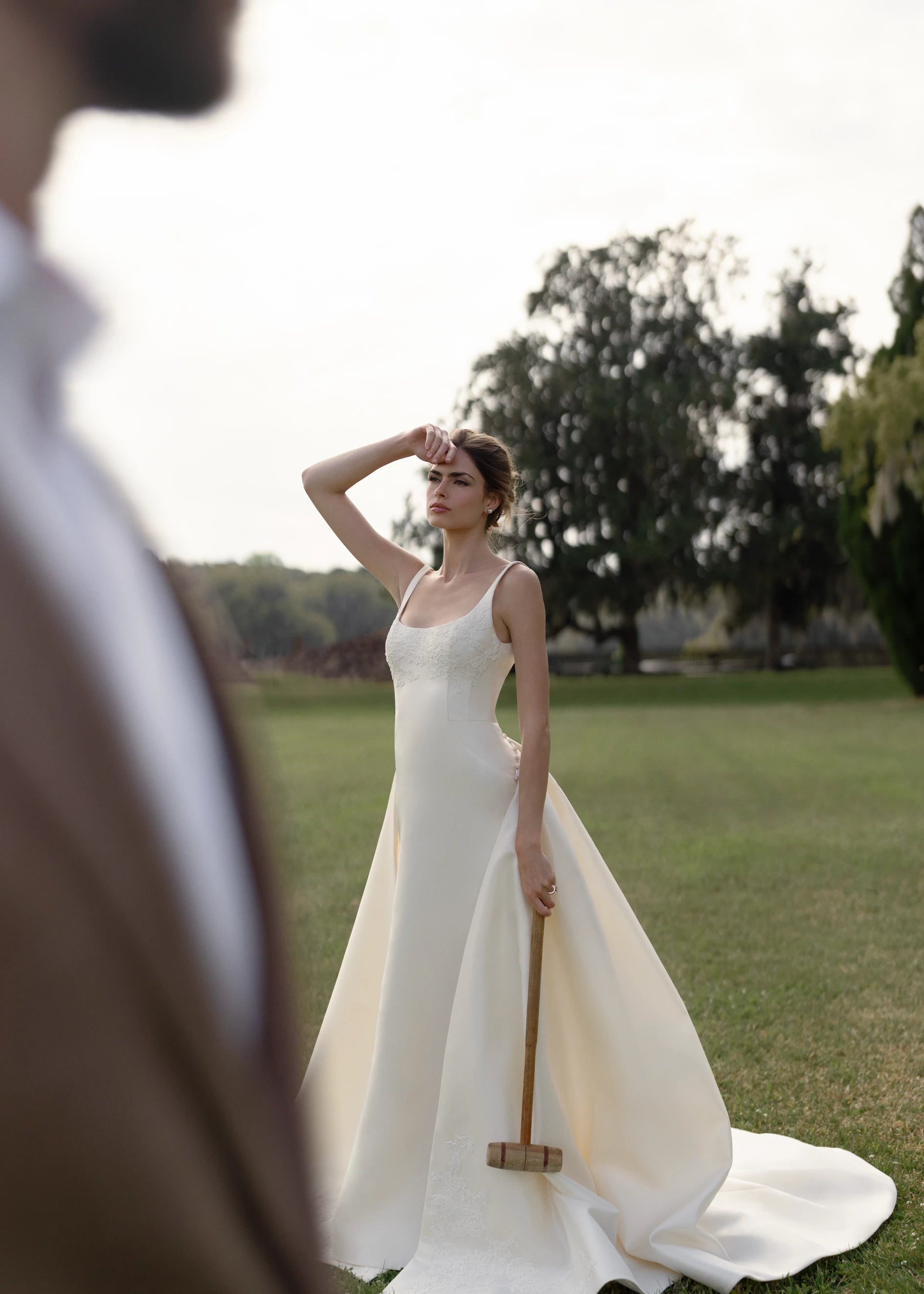 The Henrietta gown is a soft scoop neck trumpet gown of Italian Kalika with architectural seaming, featuring French Alençon lace framing the neckline.