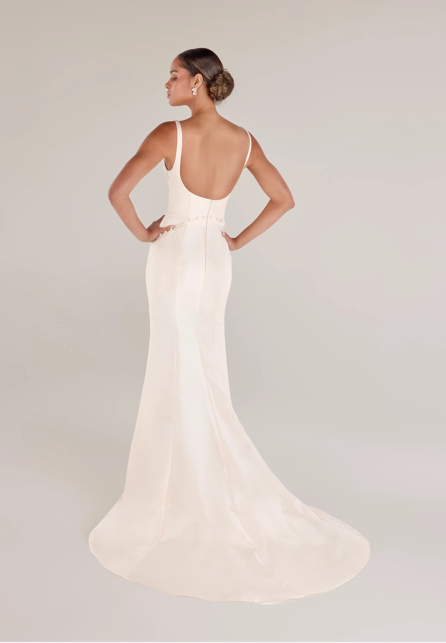 The Henrietta gown is a soft scoop neck trumpet gown of Italian Kalika with architectural seaming, featuring French Alençon lace framing the neckline in Pearl and Silk White.