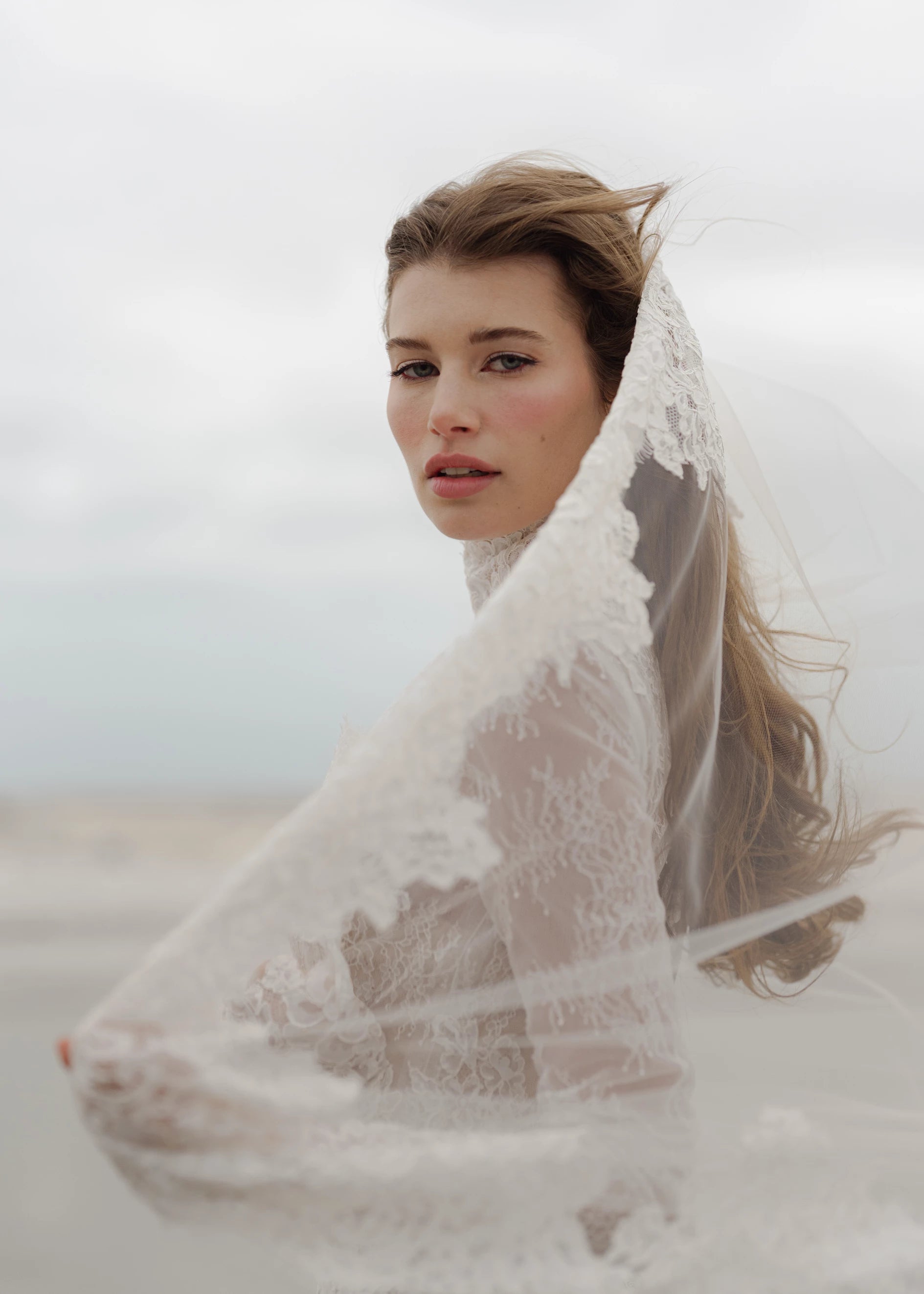 The Leo gown is a mockneck long sleeve columnar gown of Corded Lace gown with Chantilly lace underlay.