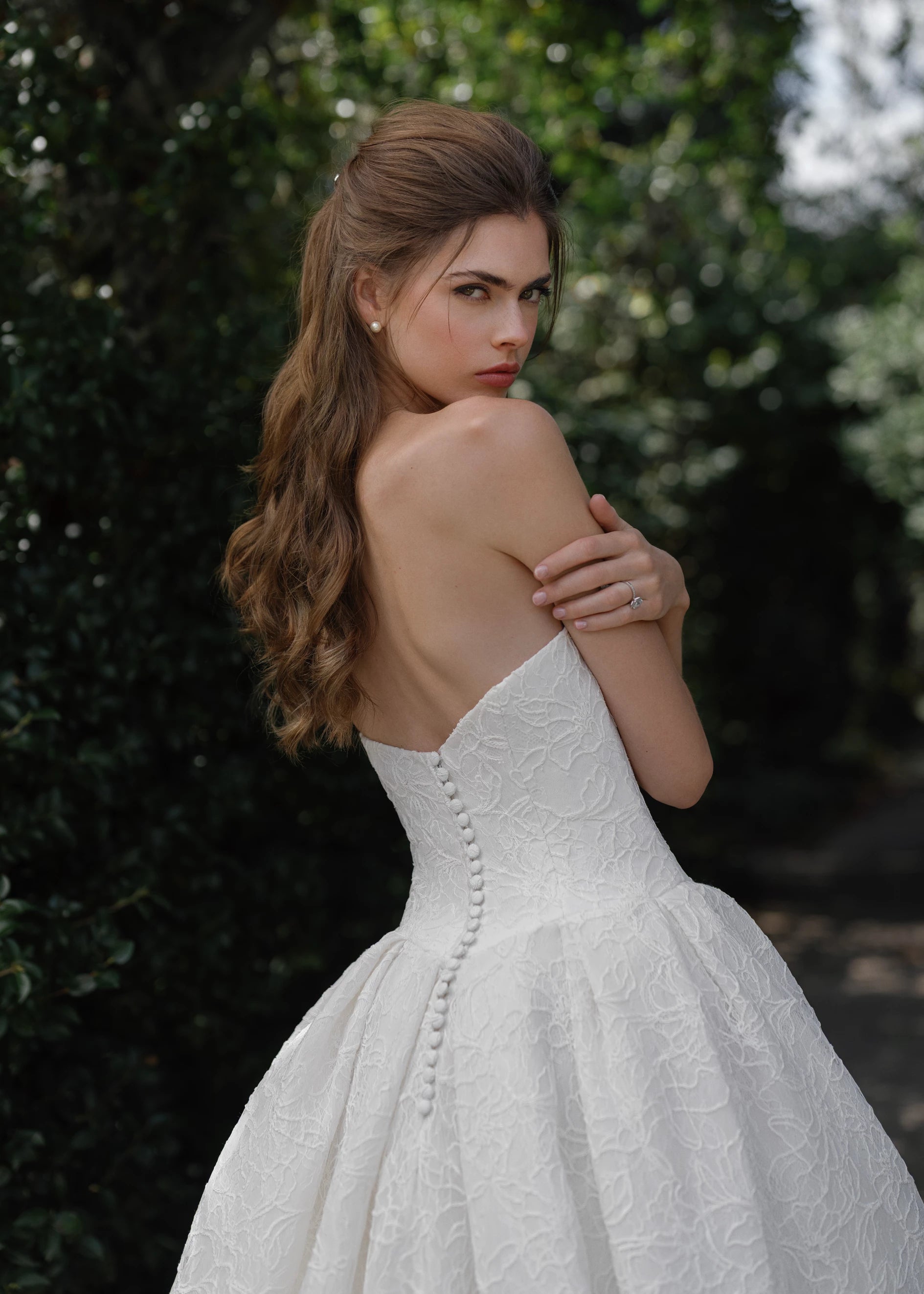 The Middleton gown is a strapless sweetheart ballgown in Corded Floral Lace with basque waist on a dramatic box pleated skirt, with buttons to the end of the zipper in Silk White.