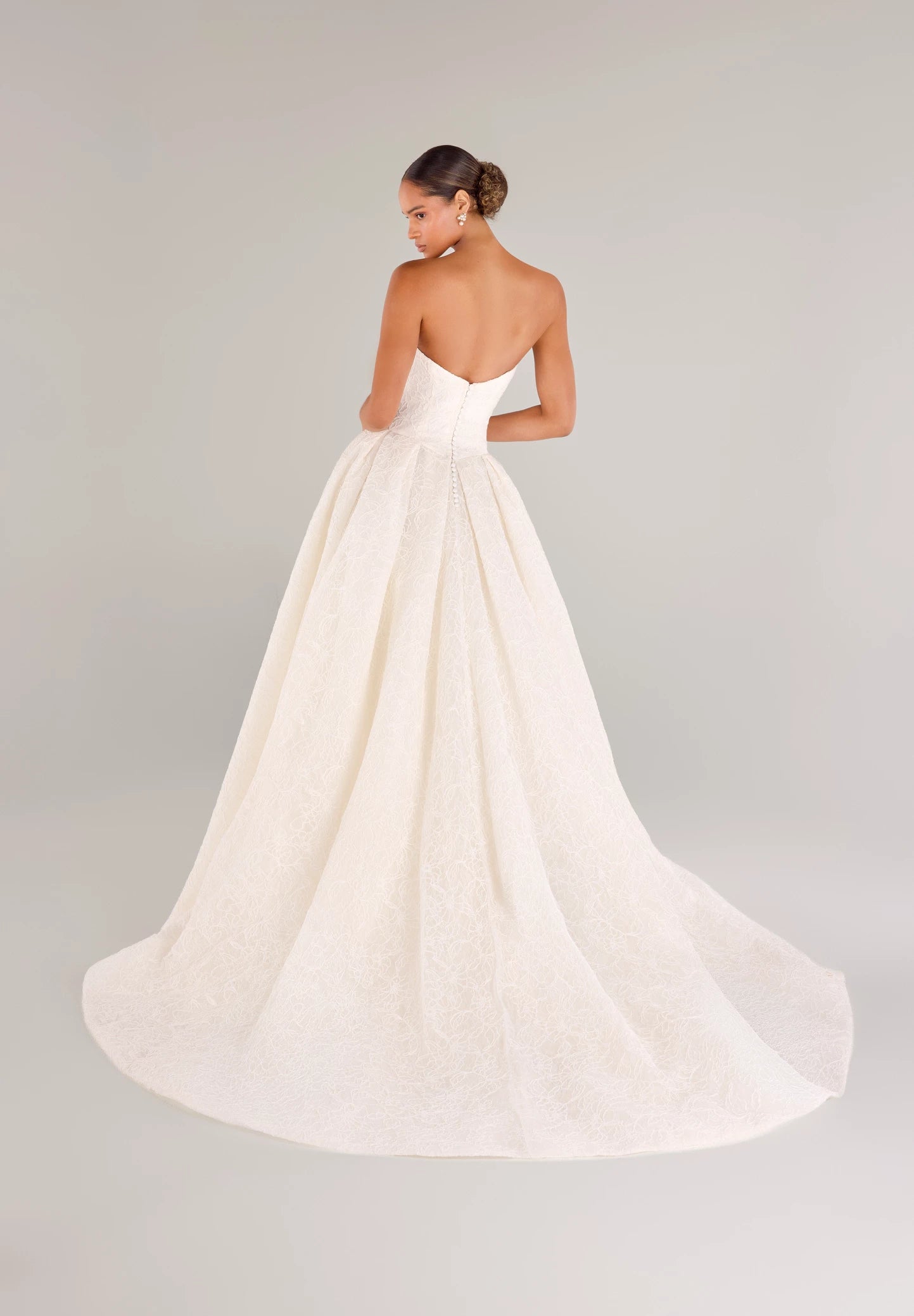 The Middleton gown is a strapless sweetheart ballgown in Corded Floral Lace with basque waist on a dramatic box pleated skirt, with buttons to the end of the zipper in Silk White.