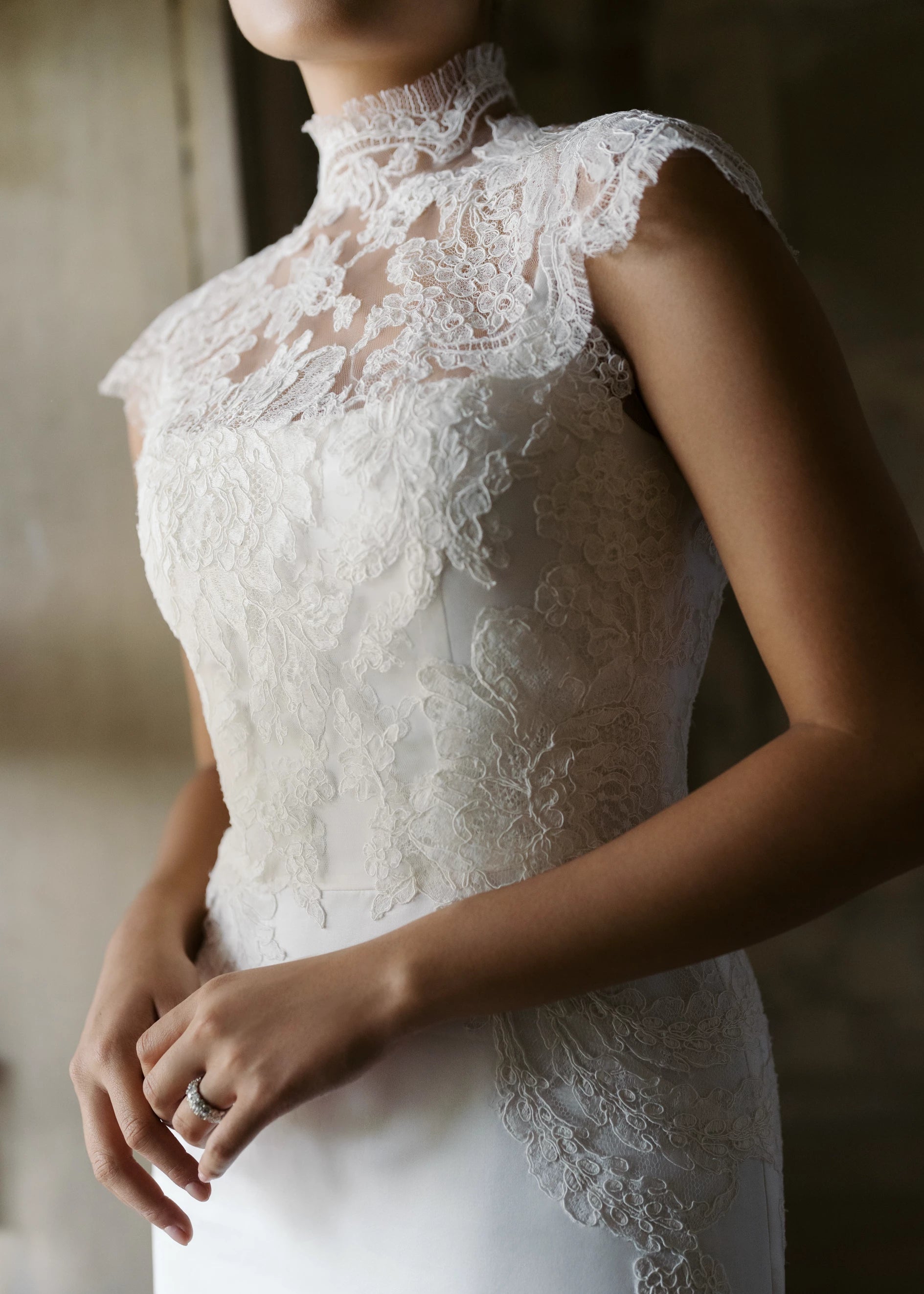 The Monet Topper by Anne Barge is a mockneck cap sleeve illusion tulle top with Alencon lace appliques and pearl buttons in Silk White.