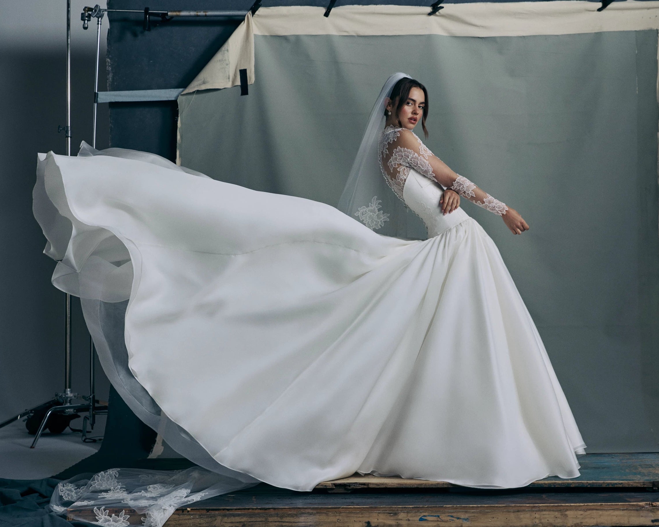 The Noblesse gown by Anne Barge is a contour strapless drop waist ball gown of Silk Satin Organza with a draped neckline, delicate French Alençon lace appliqués, and a gathered skirt finished with buttons to the hem in Silk White.Paired with the Noblesse Top, an Illusion tulle long sleeve mockneck topper appliquéd with French Alençon lace.