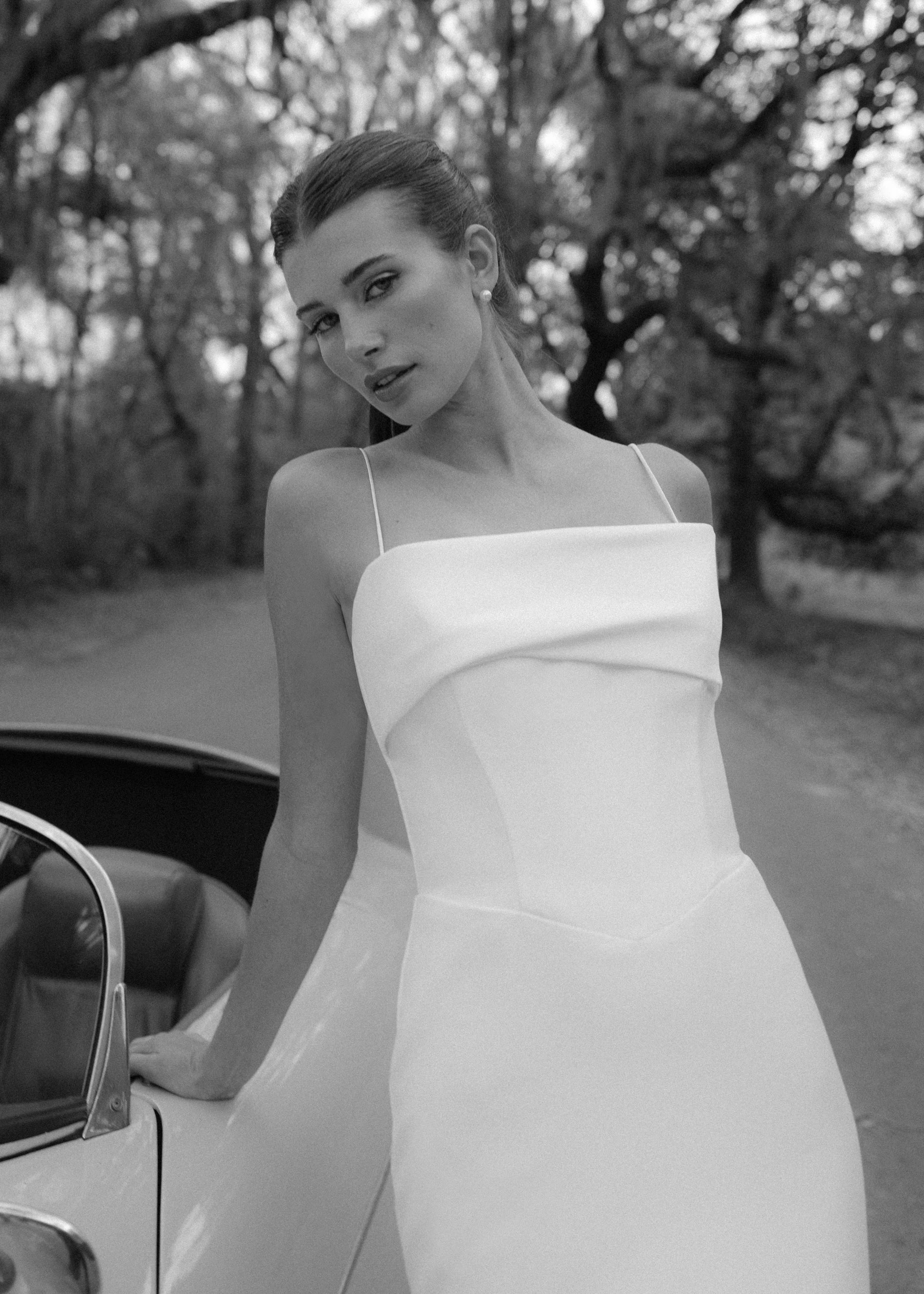 The Radcliffe gown is a spaghetti strap fit and flare gown of Soft Mikado with sculpted bodice, asymmetric bodice draping and buttons to the hem.