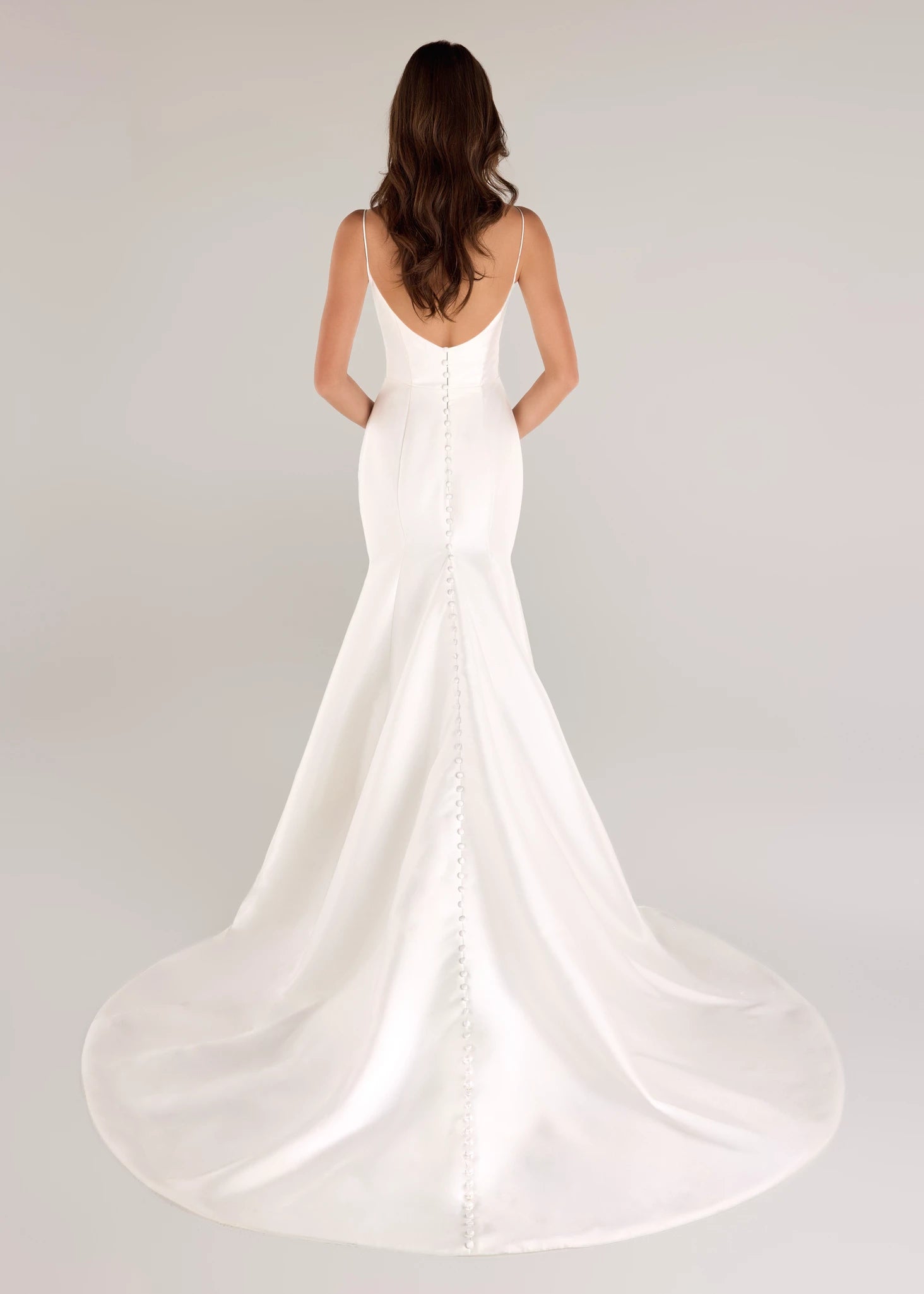 The Radcliffe gown is a spaghetti strap fit and flare gown of Soft Mikado with sculpted bodice, asymmetric bodice draping and buttons to the hem