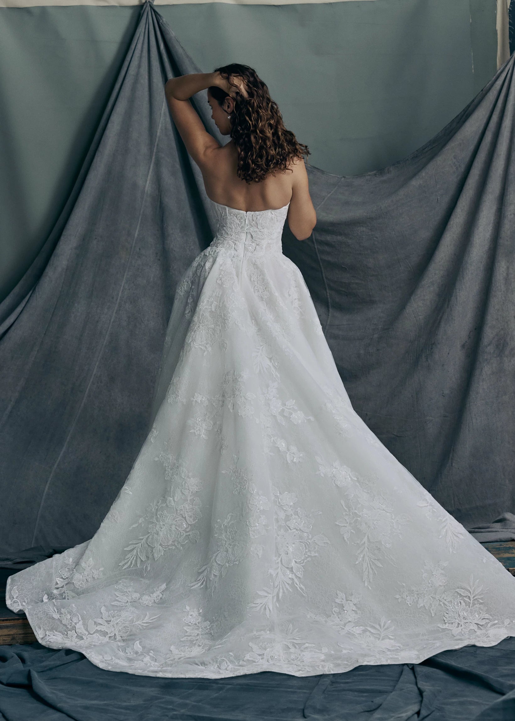 Back view of the Regalia gown by Anne Barge is a scoopneck strapless tulle ballgown, with slightly dropped waist, adorned with trickling Beaded Embroidered Appliques over Chantilly lace.