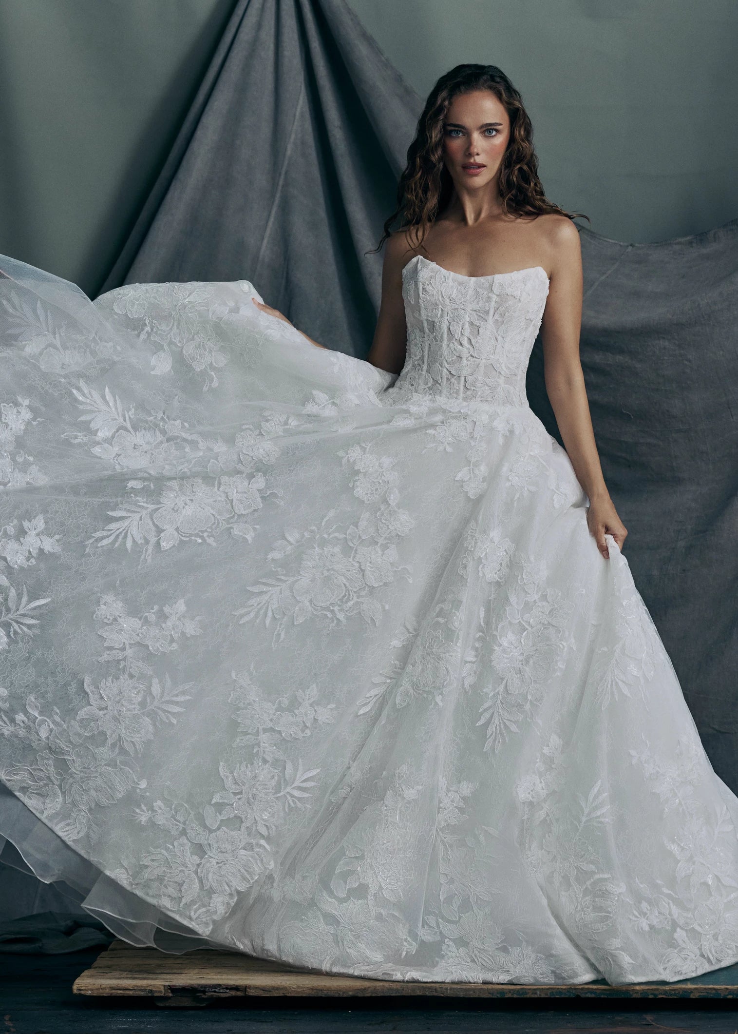 The Regalia gown by Anne Barge is a scoopneck strapless tulle ballgown, with slightly dropped waist, adorned with trickling Beaded Embroidered Appliques over Chantilly lace.