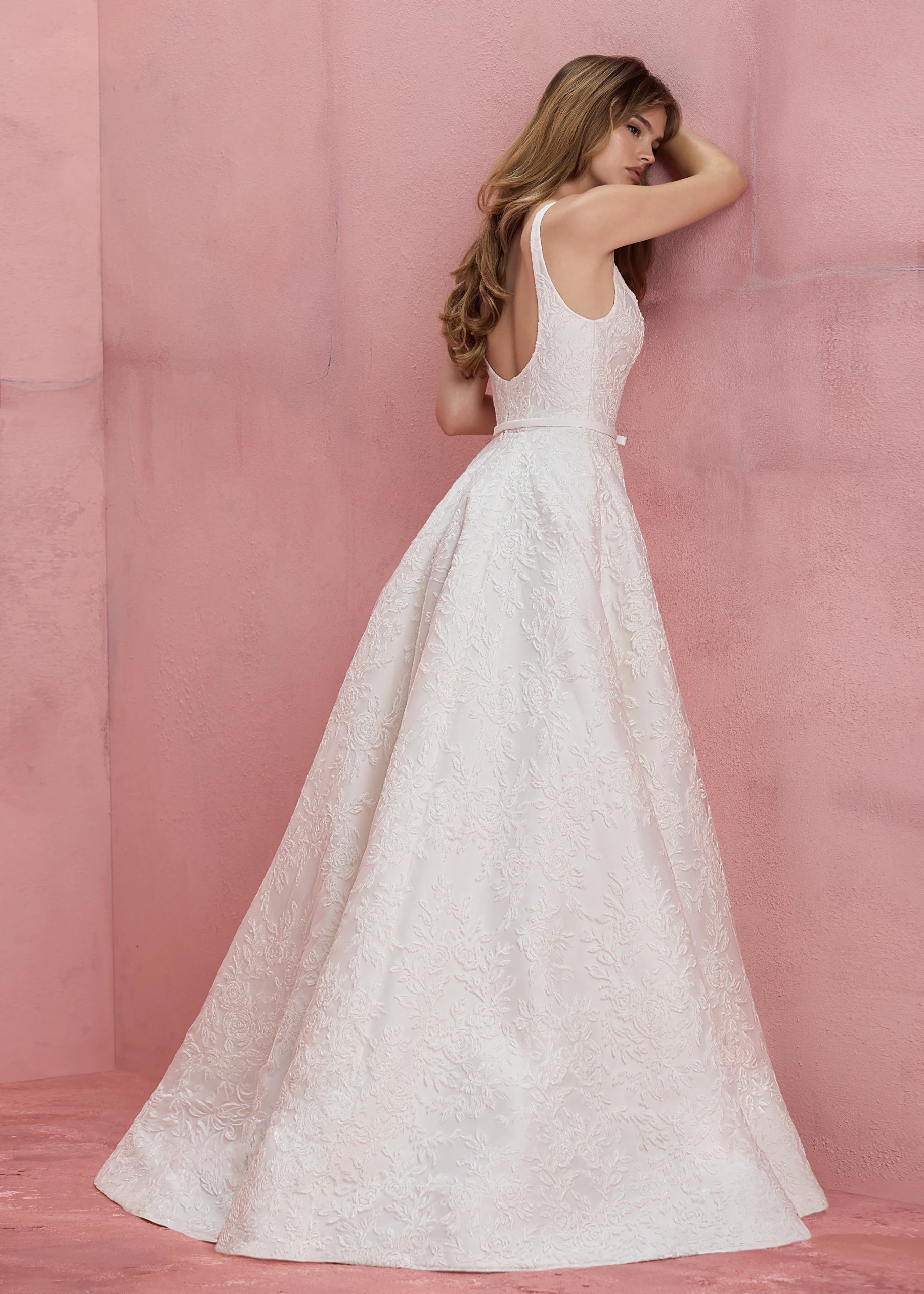 Back view of the Amelie gown is a scoop neck A-line gown in Soft Mikado with Thread-Sketched Floral Embroidery overlay, buttons to the hem and faille bow belt in Pearl.
