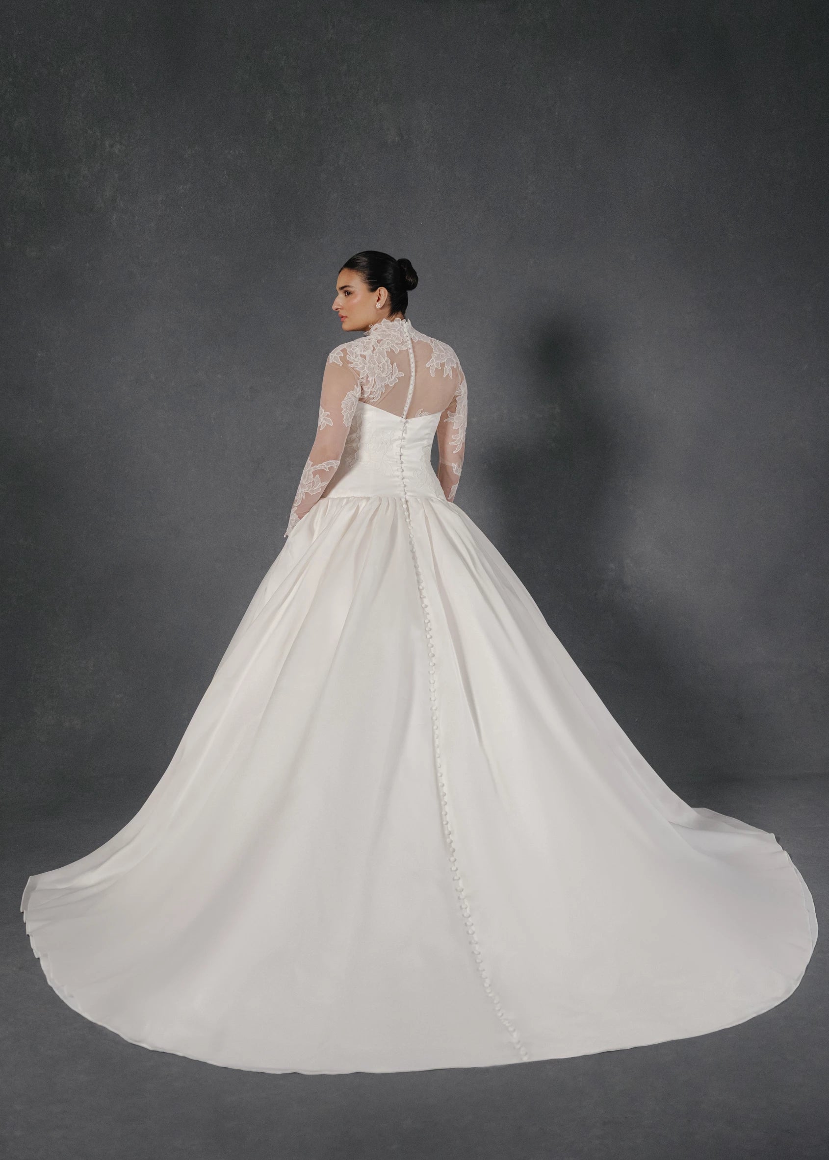 The Noblesse gown is a contour strapless drop waist ball gown of Silk Satin Organza with a draped neckline, delicate French Alençon lace appliqués, and a gathered skirt finished with buttons to the hem in Silk White.