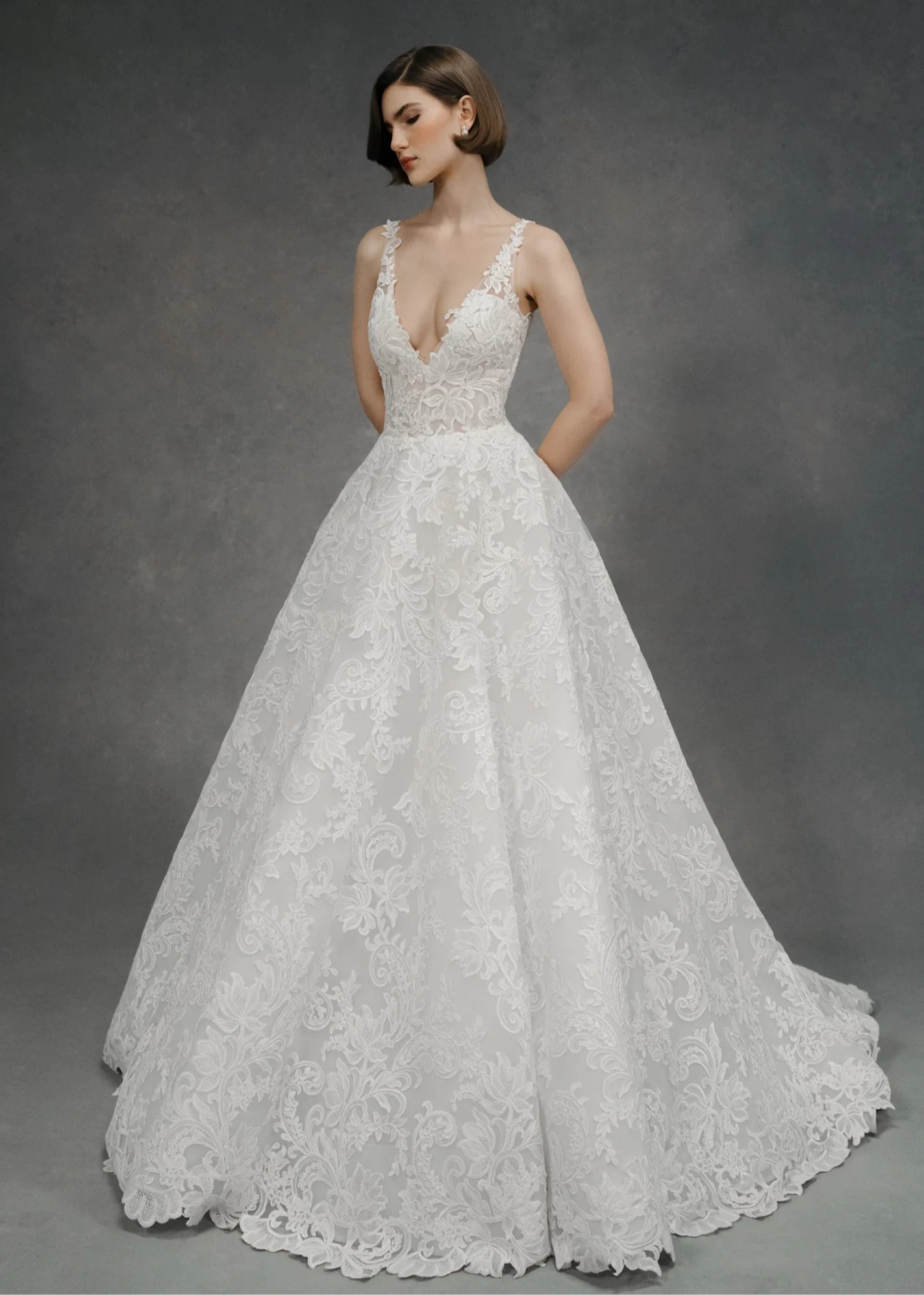 White lace anne barge wedding dress on a model against a gray background