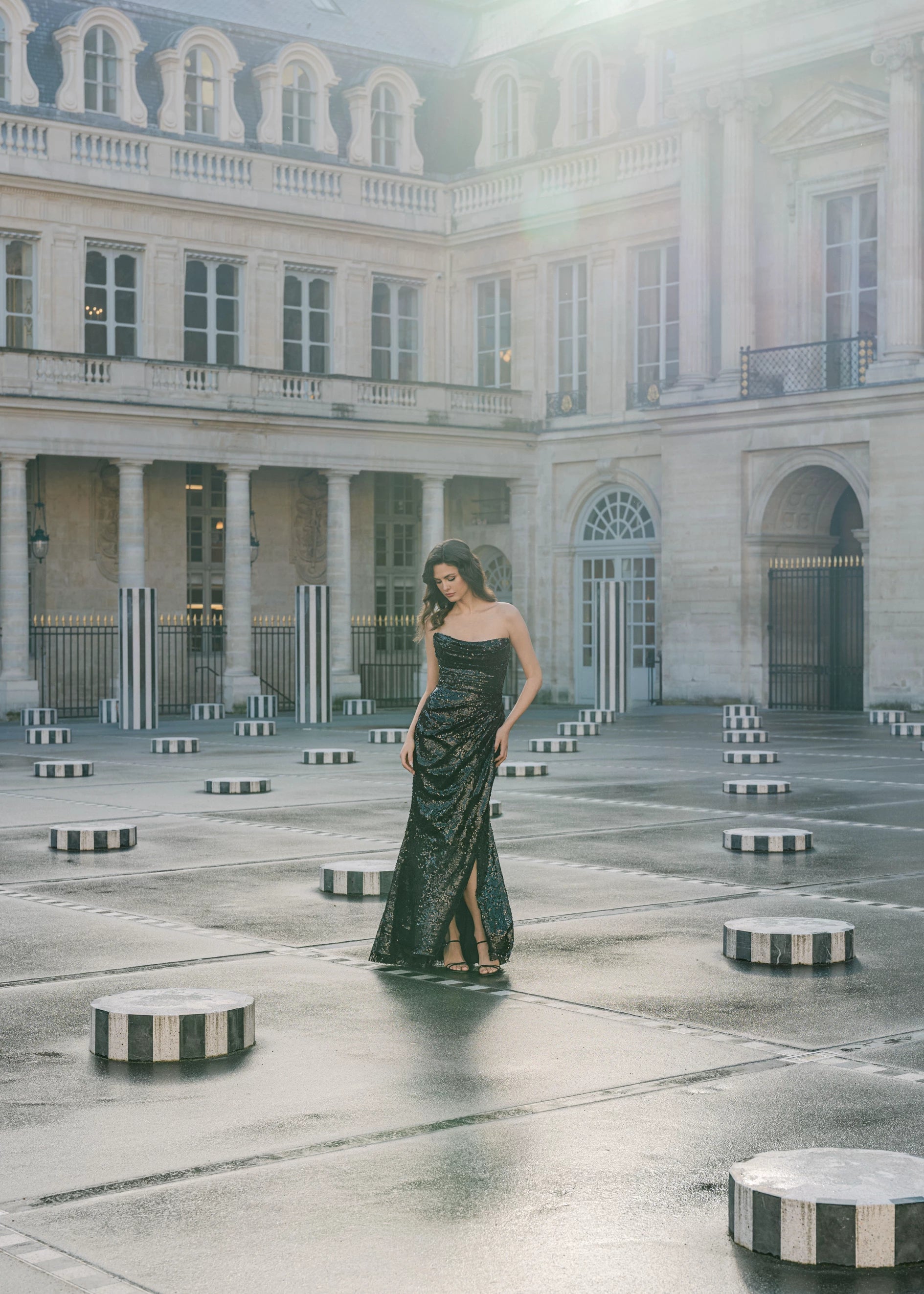 The Rivoli evening gown from Black Label by Anne Barge is a crescent neck strapless gown of Cluster Sequins with figure flattering skirt draping and asymmetric slit.