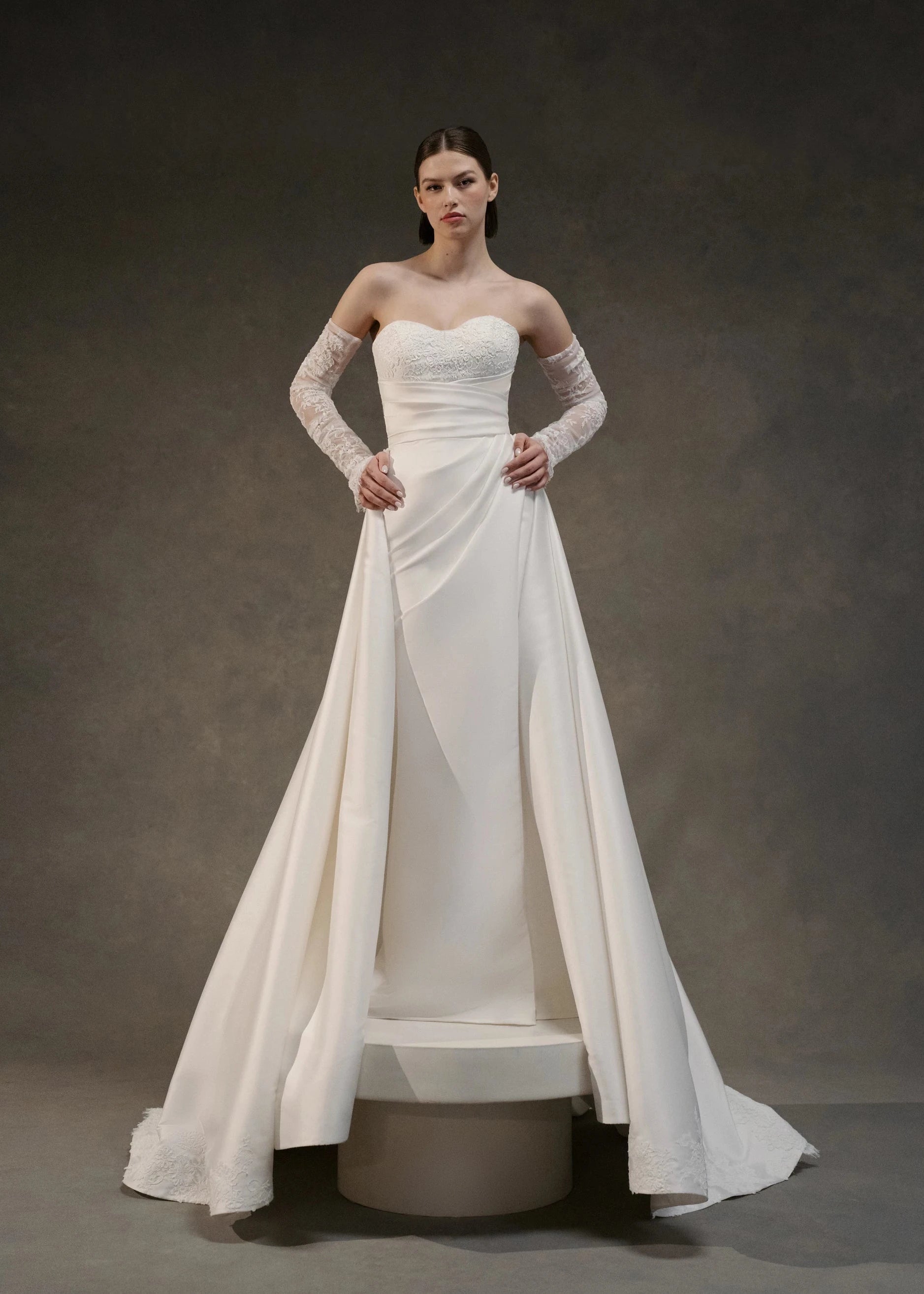 The Blue Willow Kaia Train is a dramatic detachable train of Soft Mikado, accented with a Corded Lace scalloped hem and buttons in Pearl.