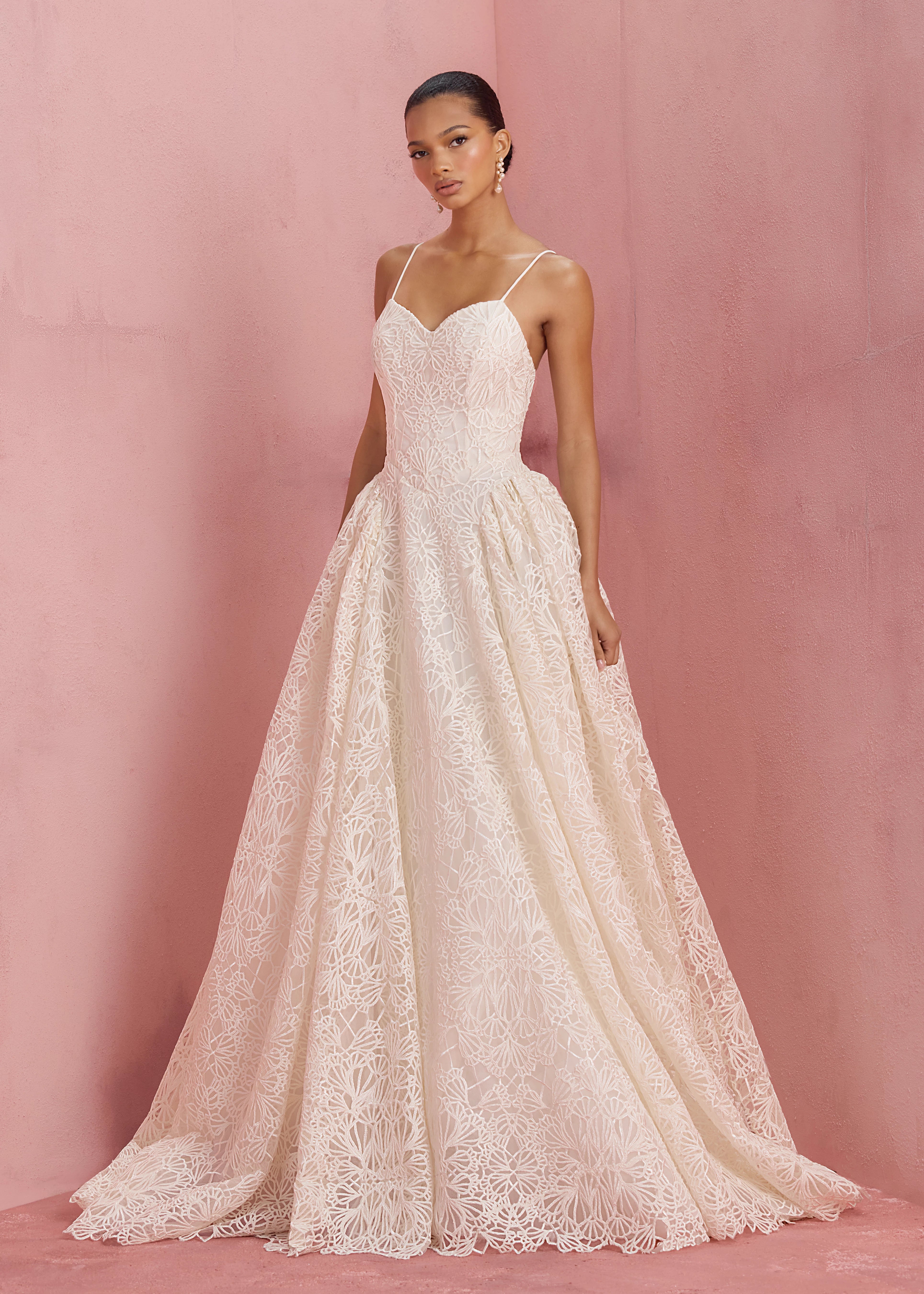 The Cecily gown is a spaghetti strap gown of Corded Satin Stitch Embroidery with basque waist, and architectural hip flares, flowing into a full A-line skirt in Pearl.