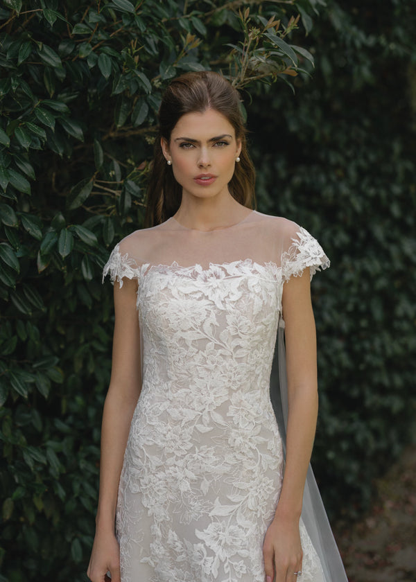 The Cromwell Cape by Anne Barge is an Illusion tulle cape with cascading Threaded Floral Embroidery, attaching at the front neckline and extending into a chapel length train in Silk White. 