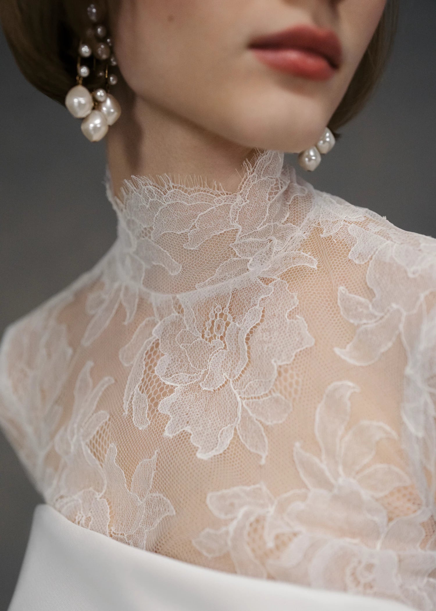 The Cyrus Topper by Anne Barge, a long sleeve mockneck top of Chantilly lace with lace-covered buttons and loops at back and wrists in Silk White. 