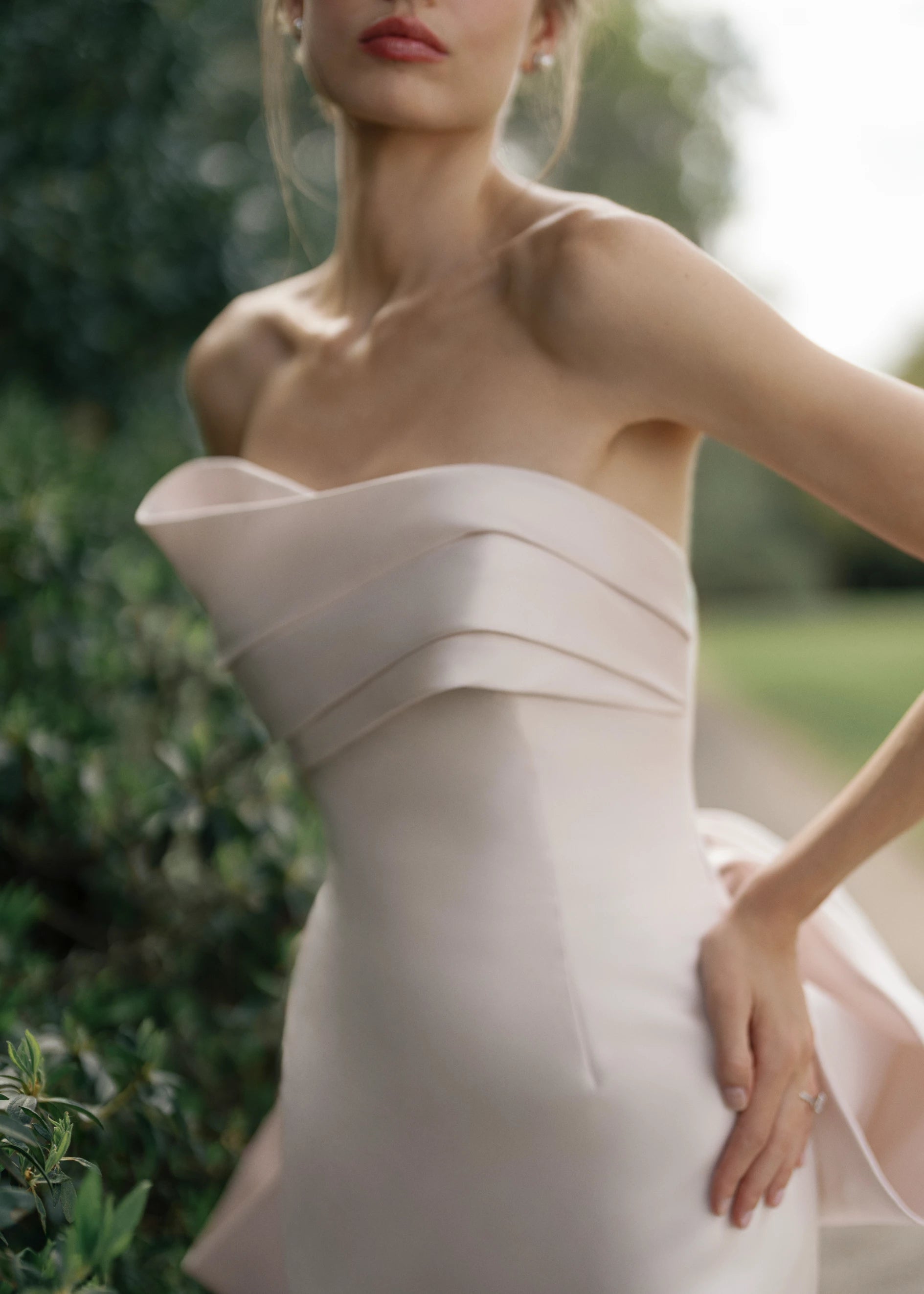 The Daniels gown is a fit and flare gown of Kalika featuring an asymmetrically draped bodice cuff, oversized sculptural bow, and buttons to the hem.