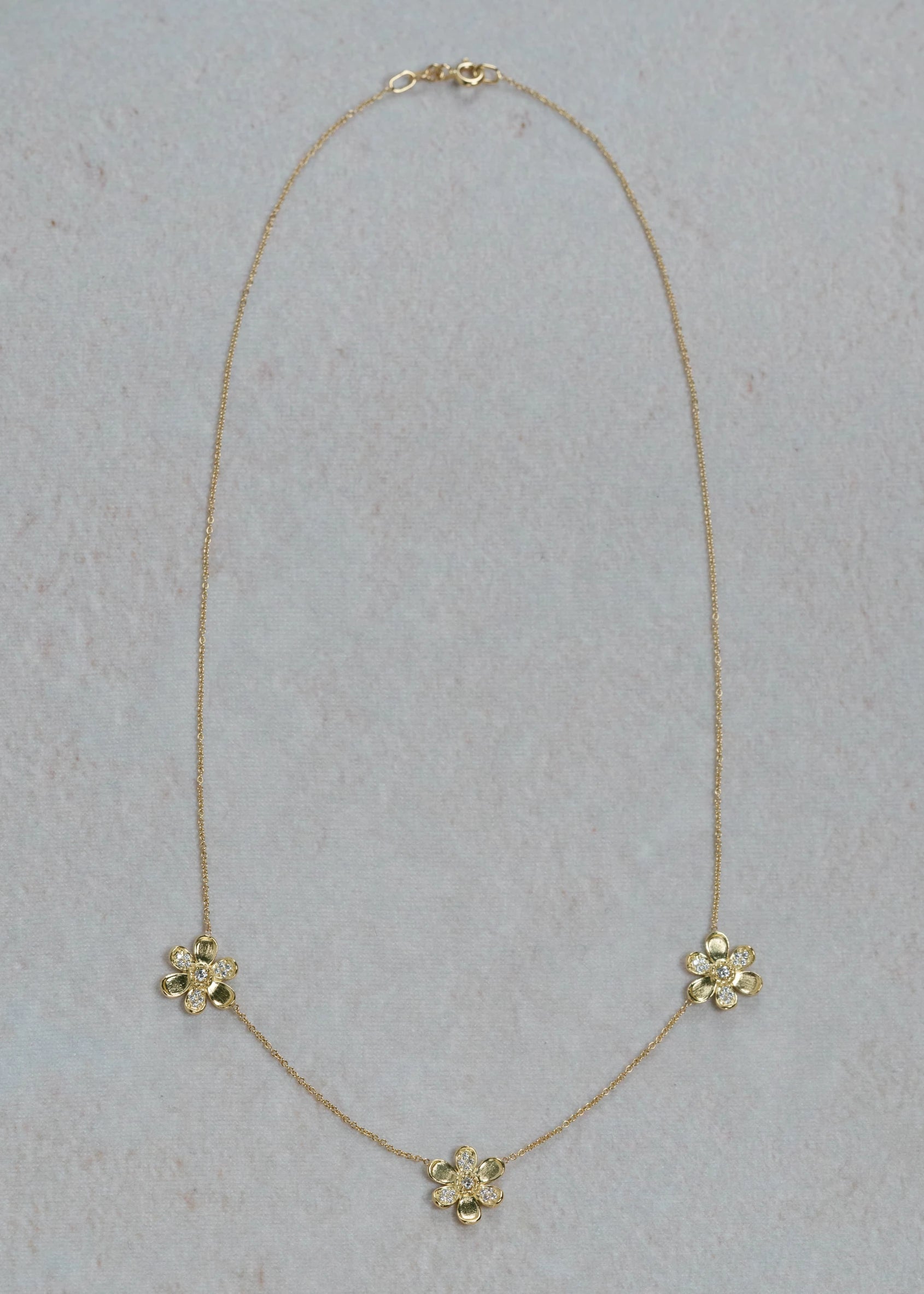 Designed by Atlanta jewelry designer Laura Pearce, three delicate pavé diamond flowers on a 16" strand, featuring 0.27 CTTW of brilliant diamonds and available in 18K Yellow or White Gold.