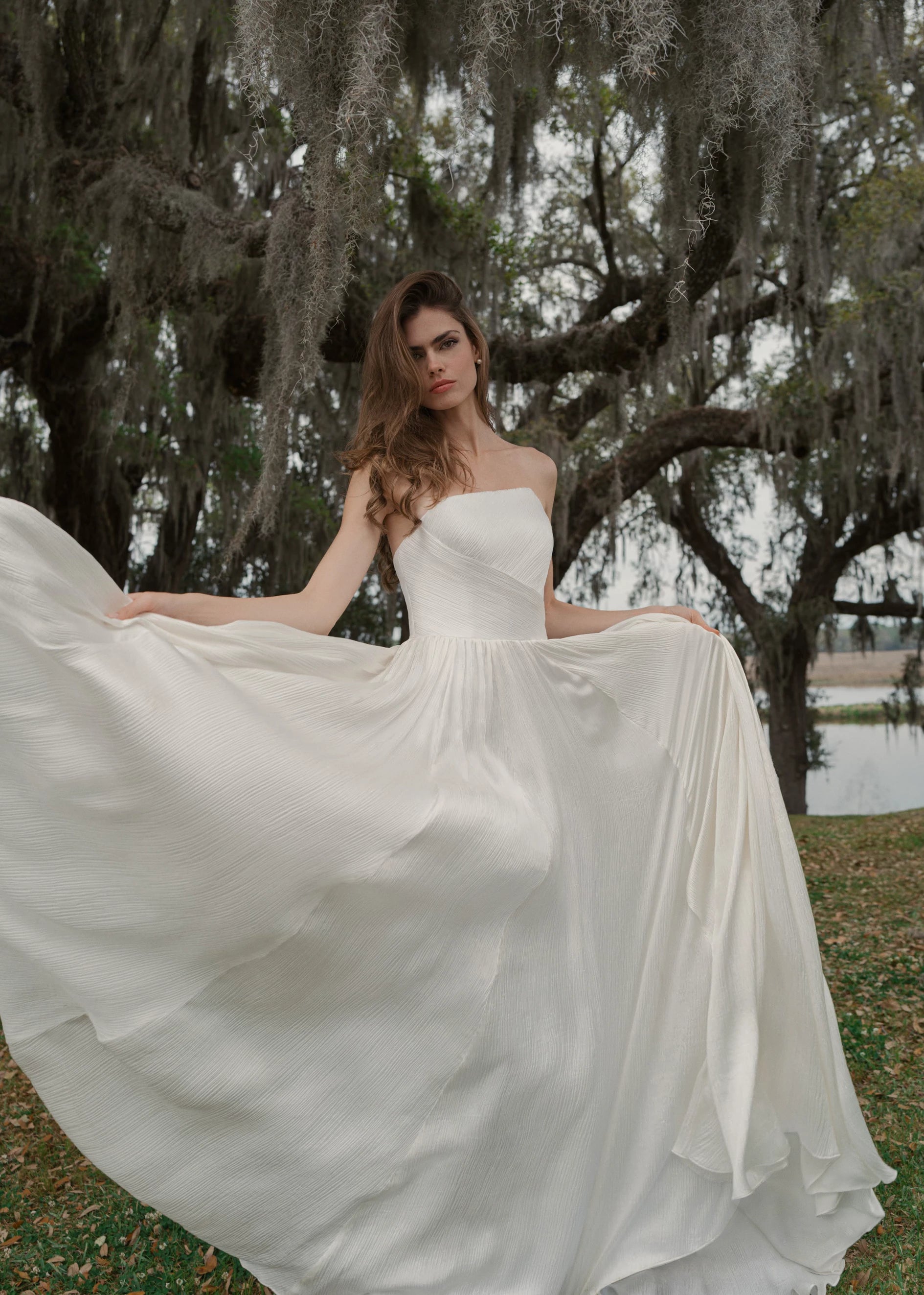 The Harelston gown is an A-line Crinkle Chiffon gown with softly gathered skirt and an asymmetrically pleated strapless bodice in Pearl.