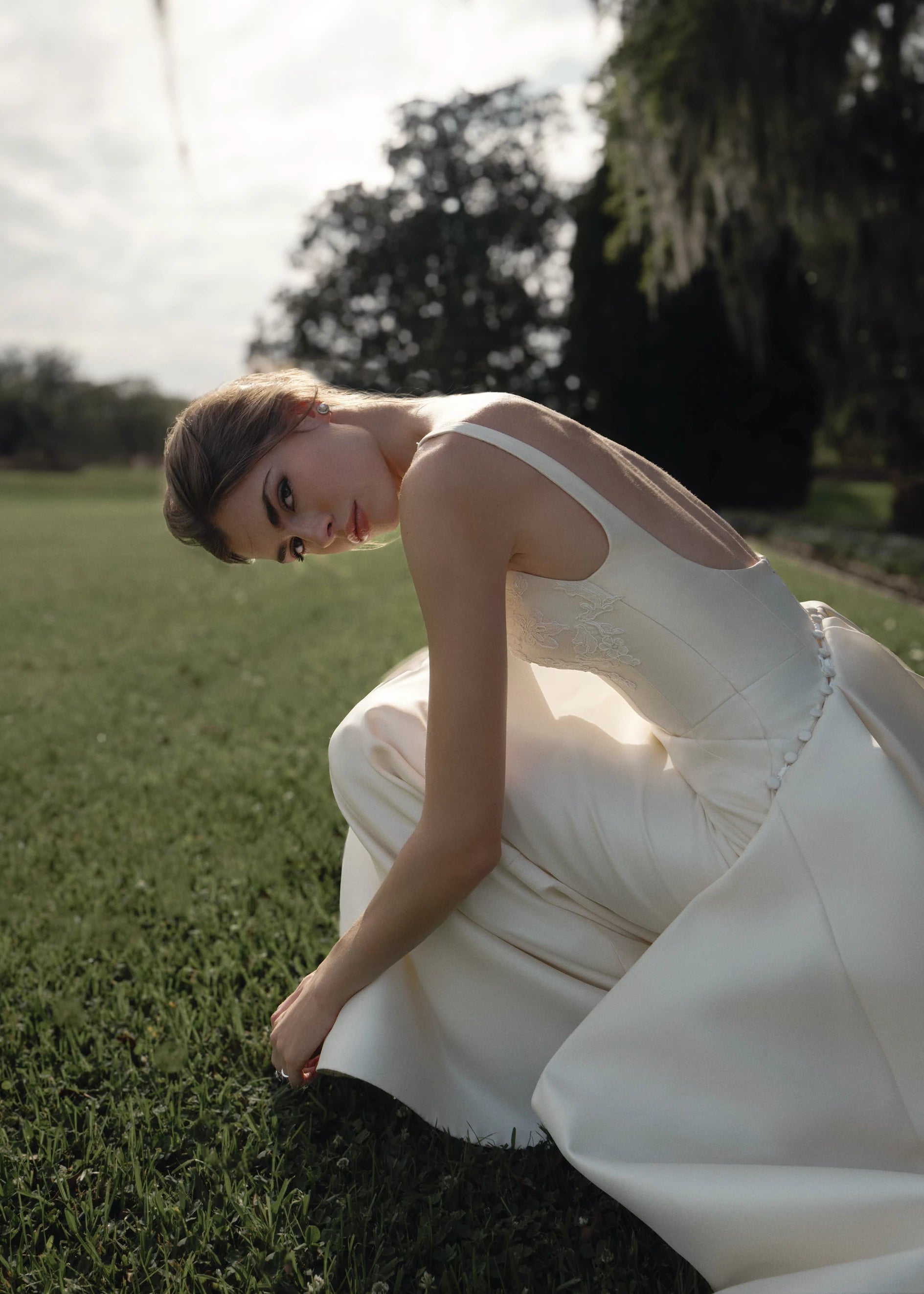 The Henrietta gown is a soft scoop neck trumpet gown of Italian Kalika with architectural seaming, featuring French Alençon lace framing the neckline.