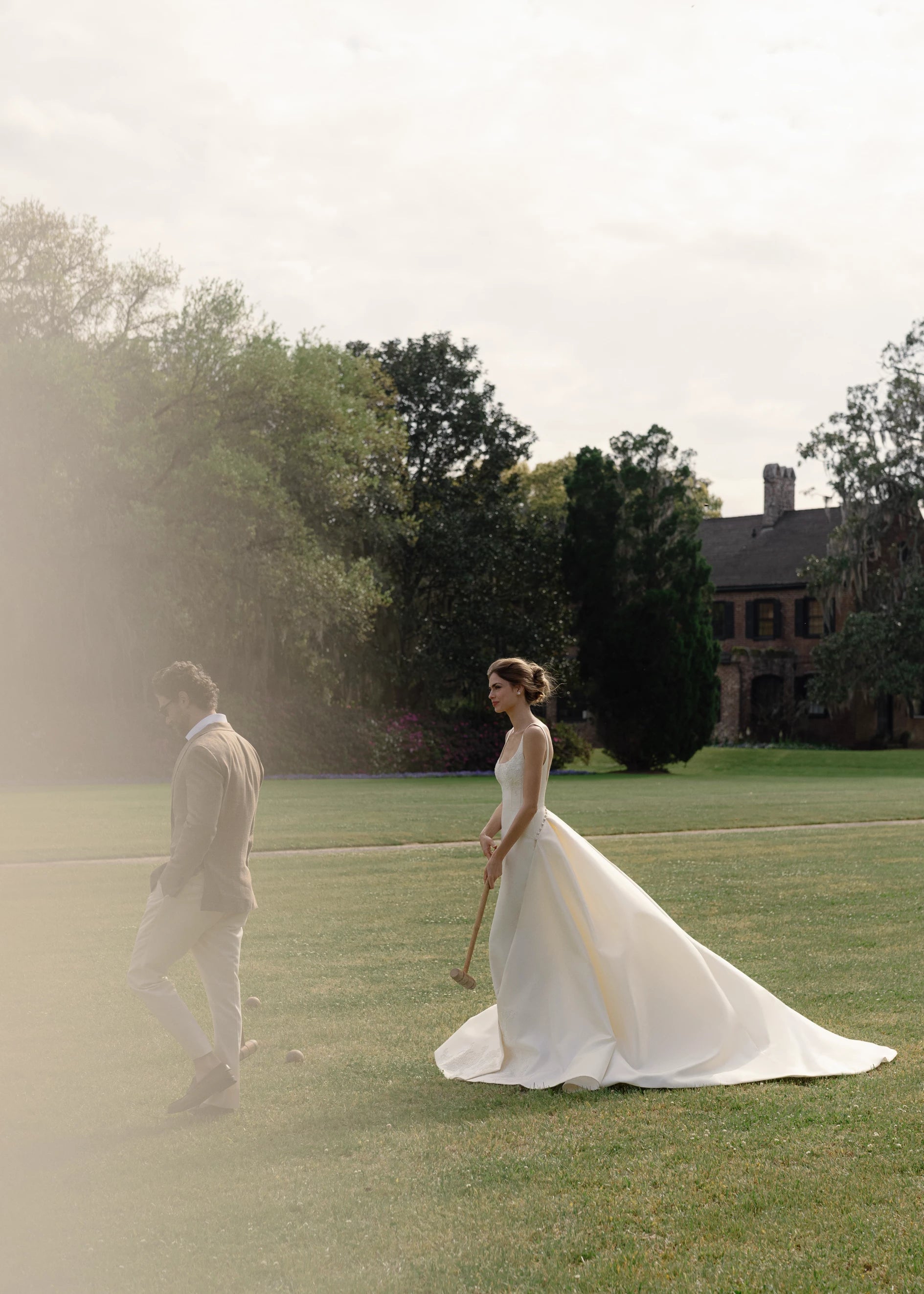 The Henrietta gown is a soft scoop neck trumpet gown of Italian Kalika with architectural seaming, featuring French Alençon lace framing the neckline.