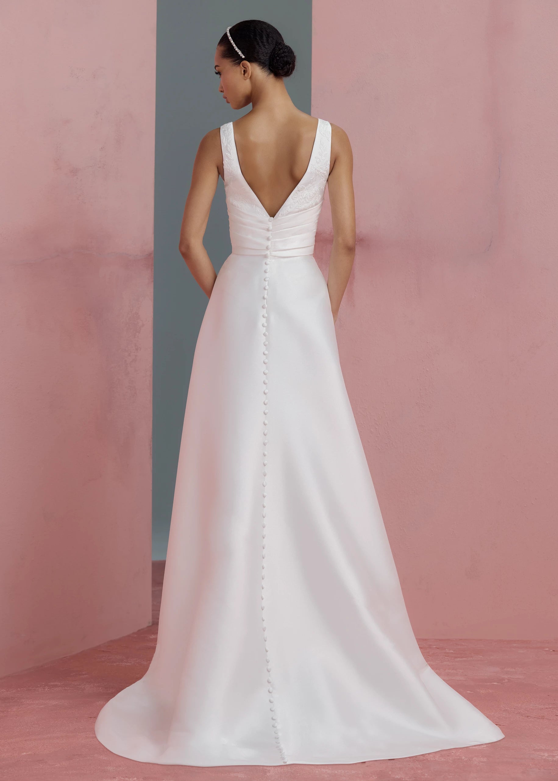 Back view of the Joelle Anne Barge gown, a soft Mikado modified A-line gown with plunging V-neckline accented with Thread-Sketched Floral Embroidered Appliques, pleated cummerbund waist, and buttons to the hem in Pearl.