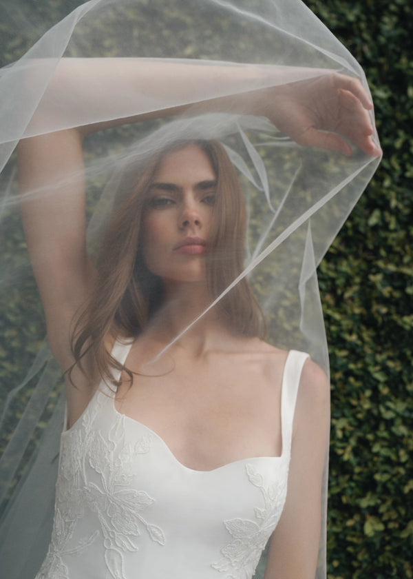 The King gown is a softly contoured sweetheart neckline A-line gown of Italian Kalika with Floral Vine Embroidered Lace appliqués framing the bodice and all around the skirt hem in Silk White.
