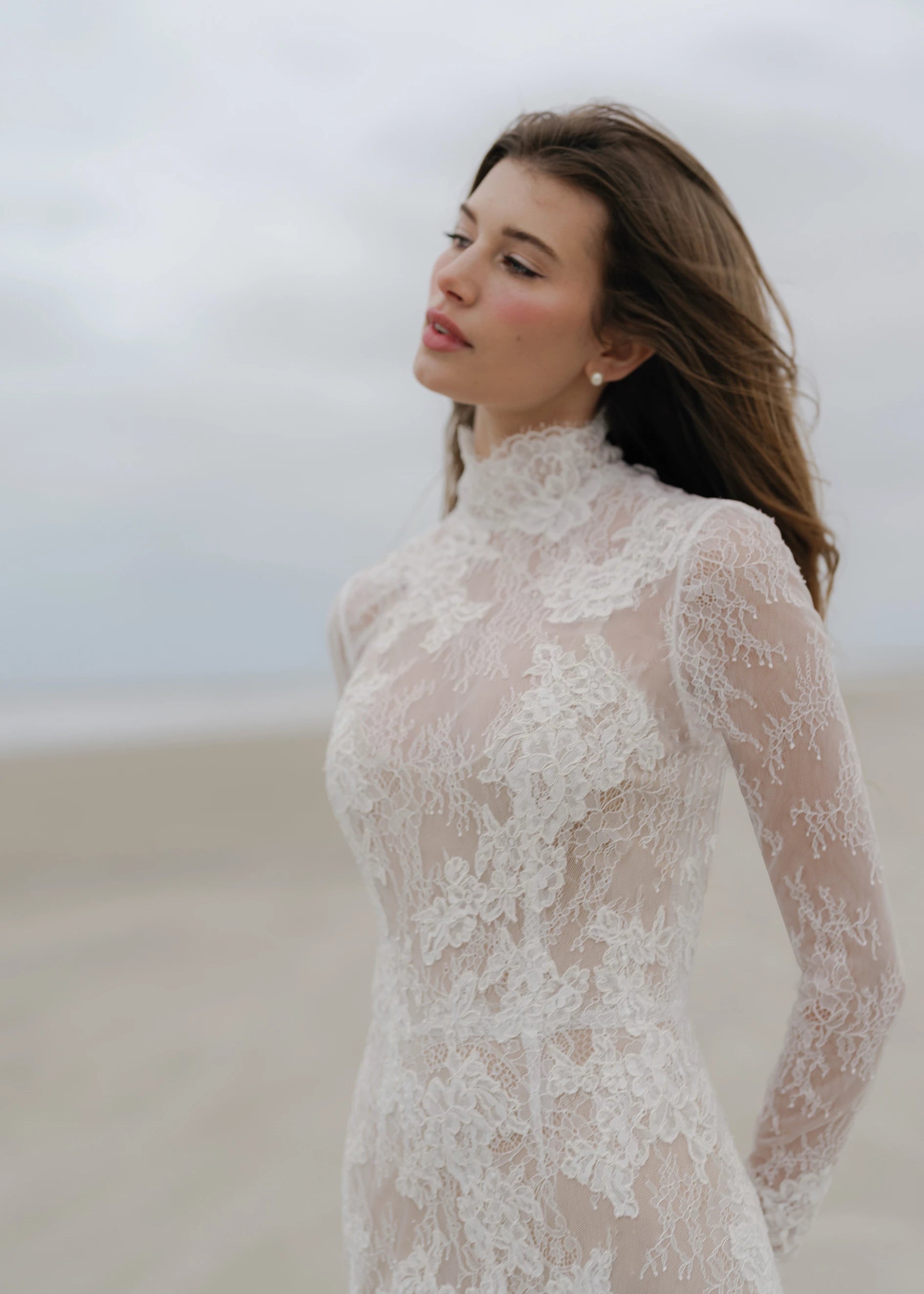 The Leo gown is a mockneck long sleeve columnar gown of Corded Lace gown with Chantilly lace underlay.