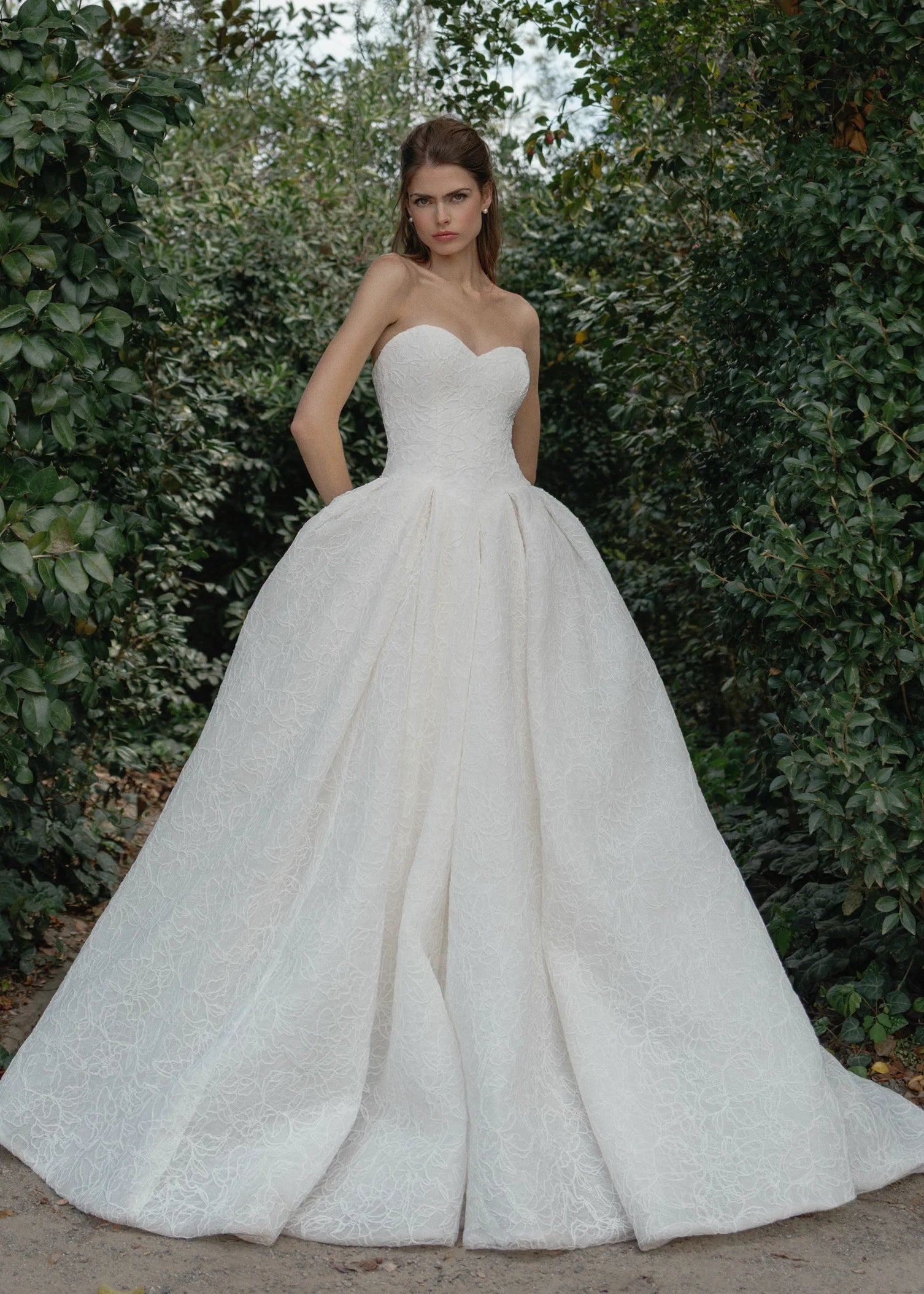 The Middleton gown is a strapless sweetheart ballgown in Corded Floral Lace with basque waist on a dramatic box pleated skirt, with buttons to the end of the zipper in Silk White. 