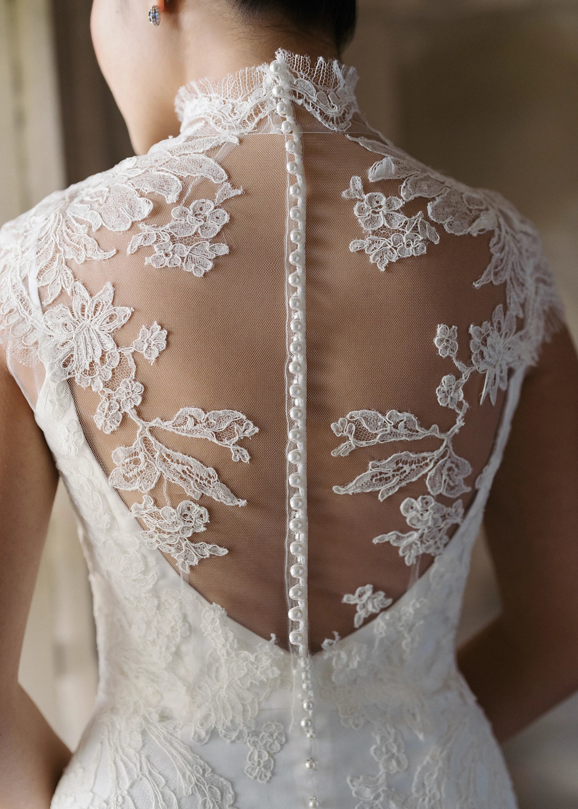 The Monet Topper by Anne Barge is a mockneck cap sleeve illusion tulle top with Alencon lace appliques and pearl buttons in Silk White. 