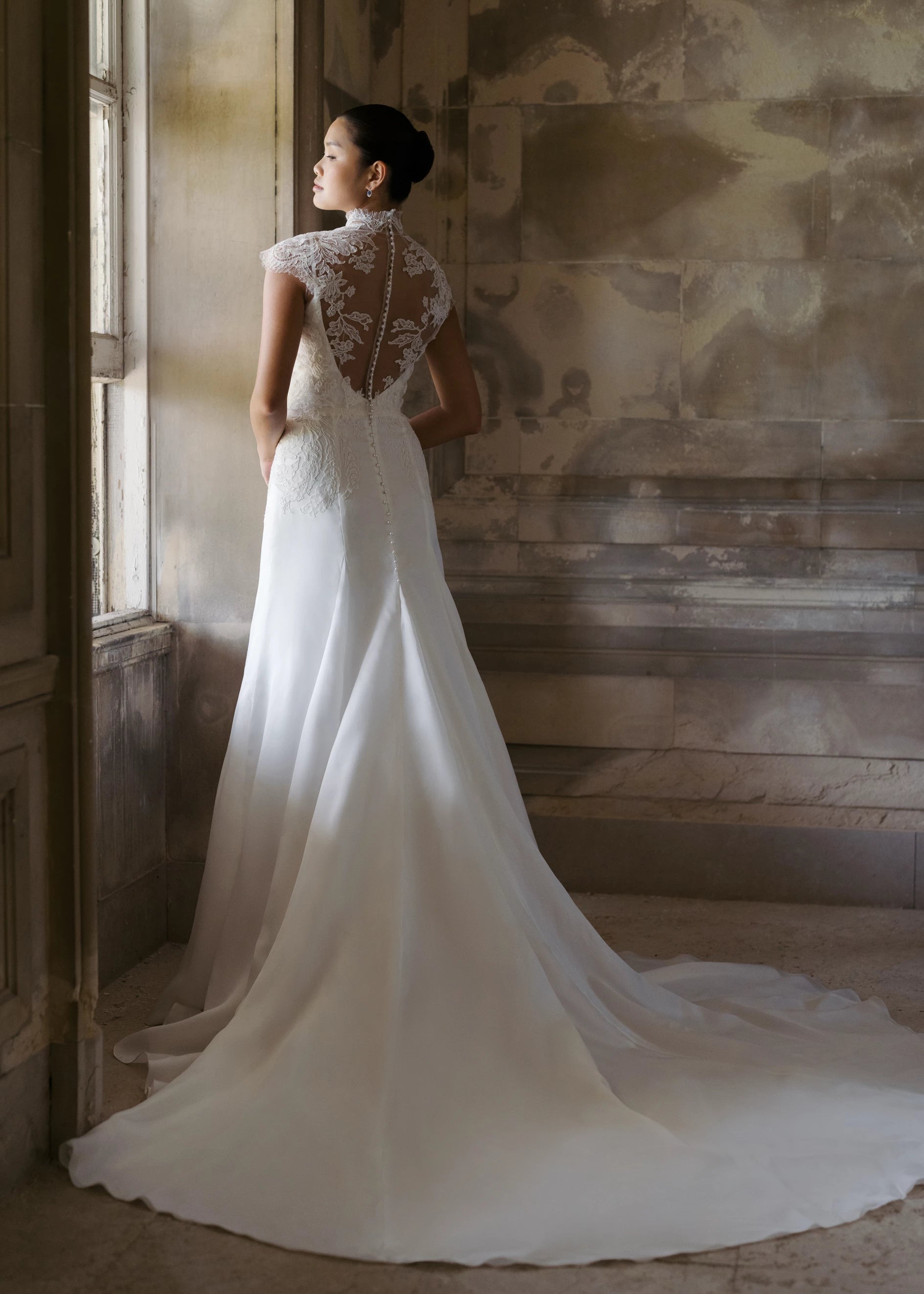 The Monet Topper by Anne Barge is a mockneck cap sleeve illusion tulle top with Alencon lace appliques and pearl buttons in Silk White. 