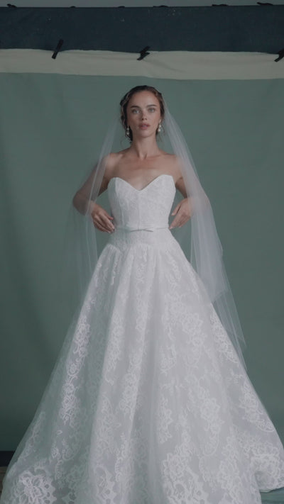 The Albertine gown by Anne Barge is a sculpted sweetheart strapless ballgown in Chantilly lace, featuring a ziggurat dropped waist and buttons to the hem in Silk White.