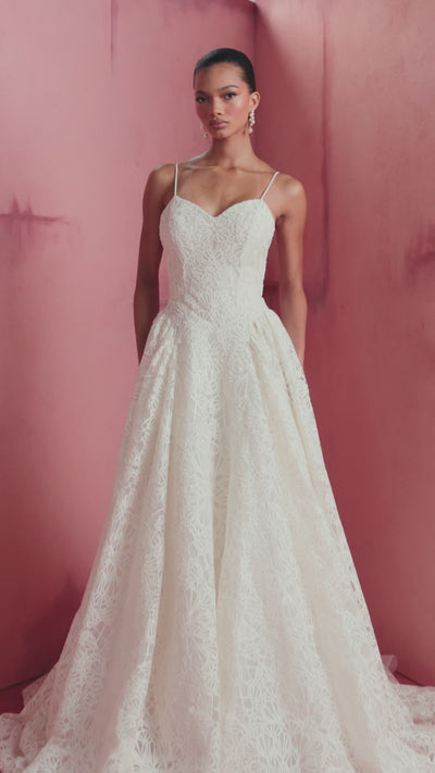 The Cecily gown is a spaghetti strap gown of Corded Satin Stitch Embroidery with basque waist, and architectural hip flares, flowing into a full A-line skirt in Pearl.