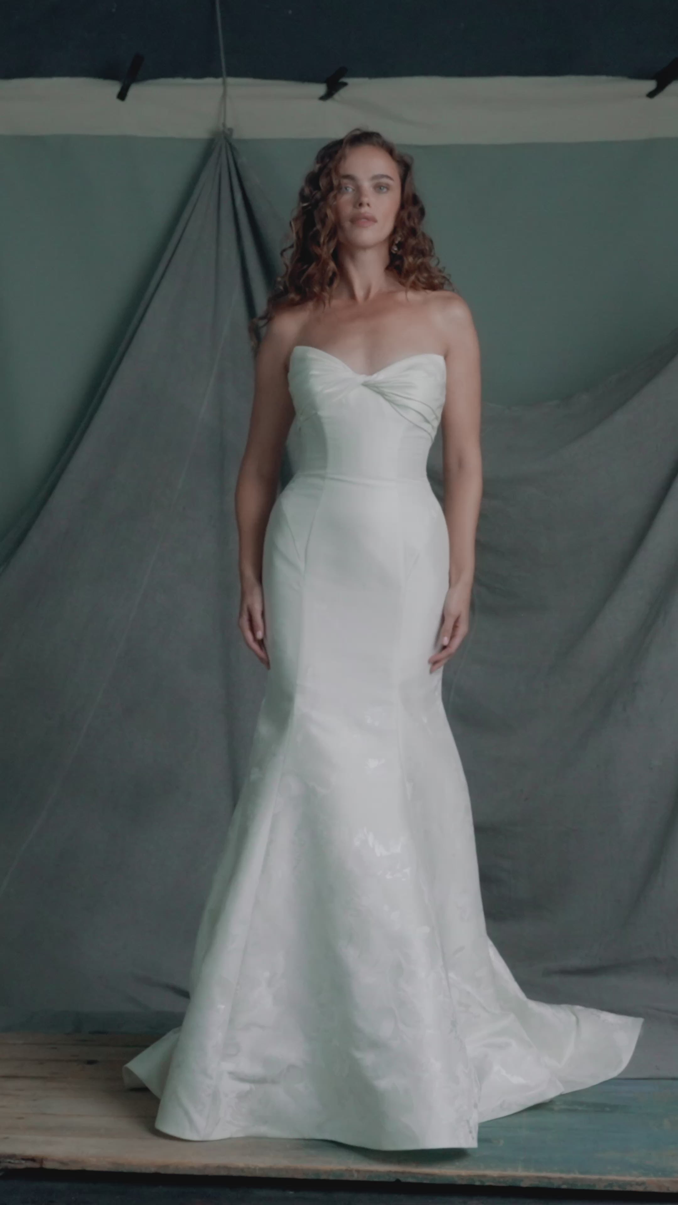 The Justine gown by Anne Barge  is a strapless sweetheart trumpet gown of Italian Floral Matte Satin Jacquard with twisted draped bodice and buttons to the hem in Pearl.