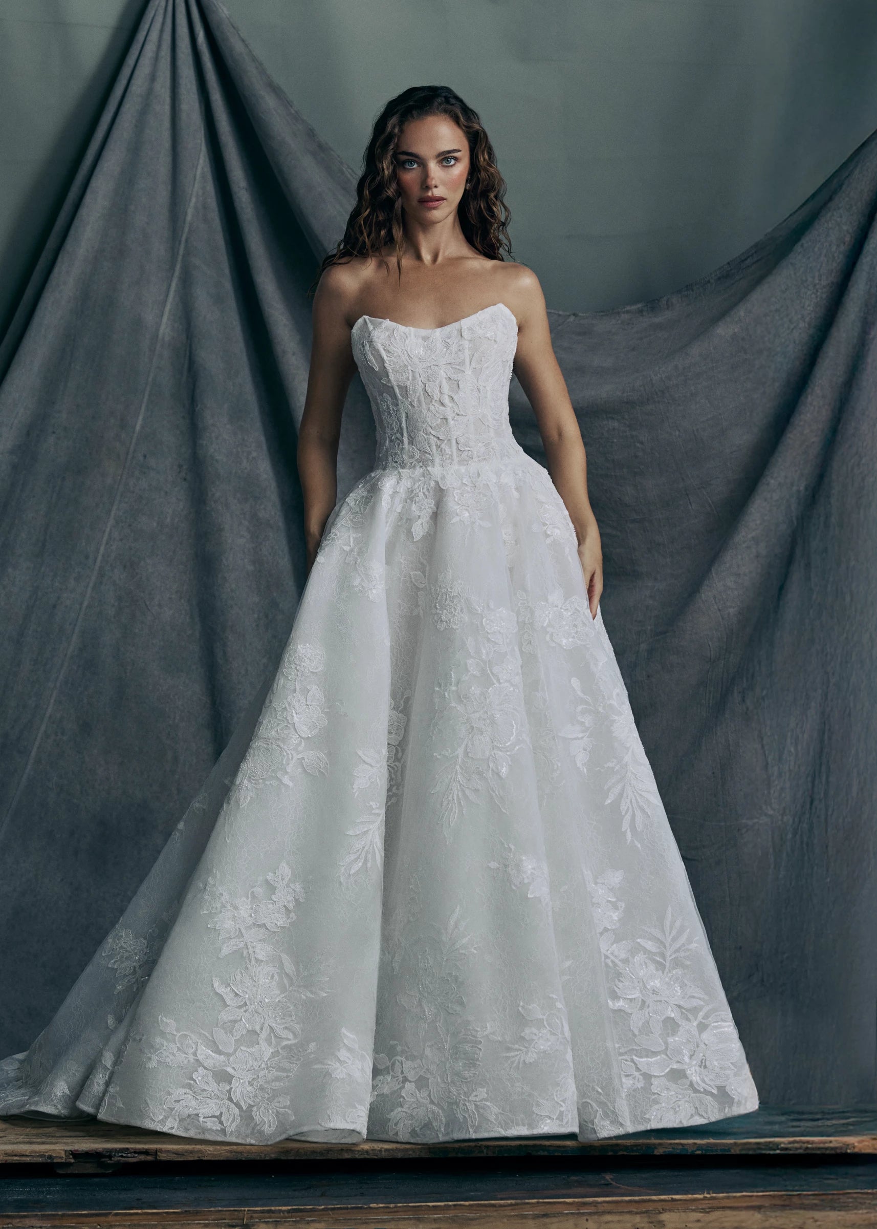 The Regalia gown by Anne Barge is a scoopneck strapless tulle ballgown, with slightly dropped waist, adorned with trickling Beaded Embroidered Appliques over Chantilly lace. 