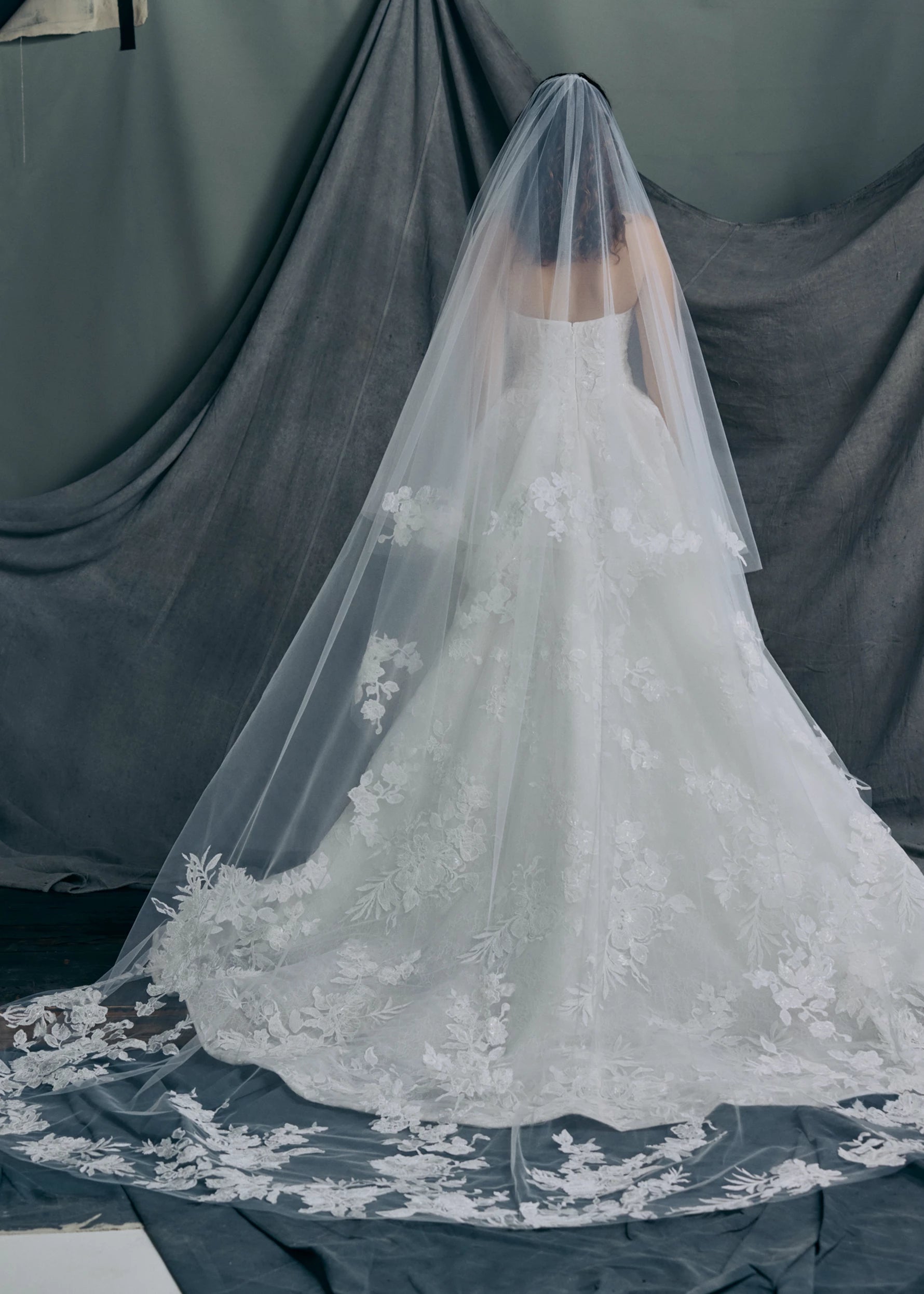 Back view of the Regalia gown by Anne Barge is a scoopneck strapless tulle ballgown, with slightly dropped waist, adorned with trickling Beaded Embroidered Appliques over Chantilly lace. Paired wit the Regalia veil.