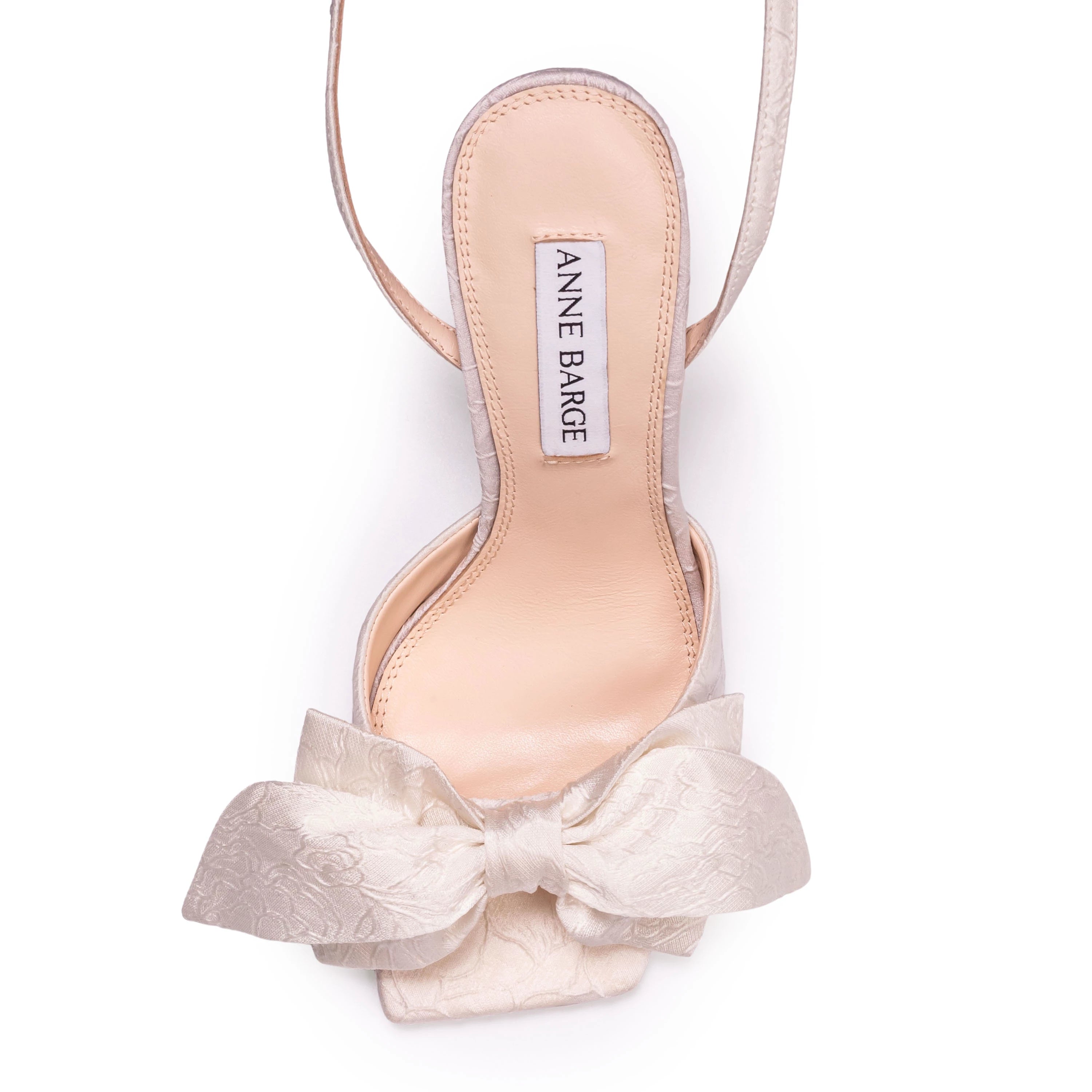 A square-toe sandal set on a timeless 90mm block heel, adorned with a crystal-embellished square buckle and a softly draped bow detail across the upper. Crafted from luxurious satin jacquard.